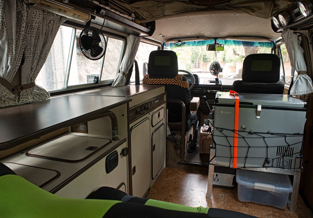 You can see the refrigerator on the right, with cargo net to store things (cleaned up for the picture but usually full of stuff) and our shoe box underneath. This refrigerator stand was probably the best thing Corbin RV did for us. The orange strap is to keep the refrigerator in place if we tumble down a mountainside.