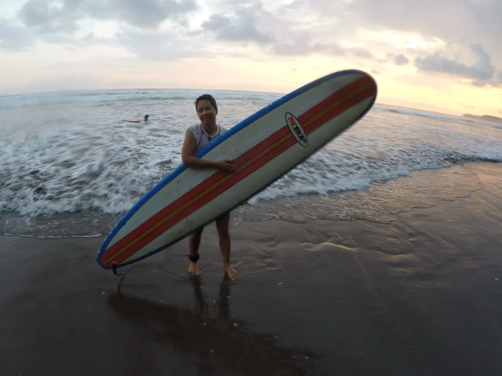 R poses with the board and ocean.