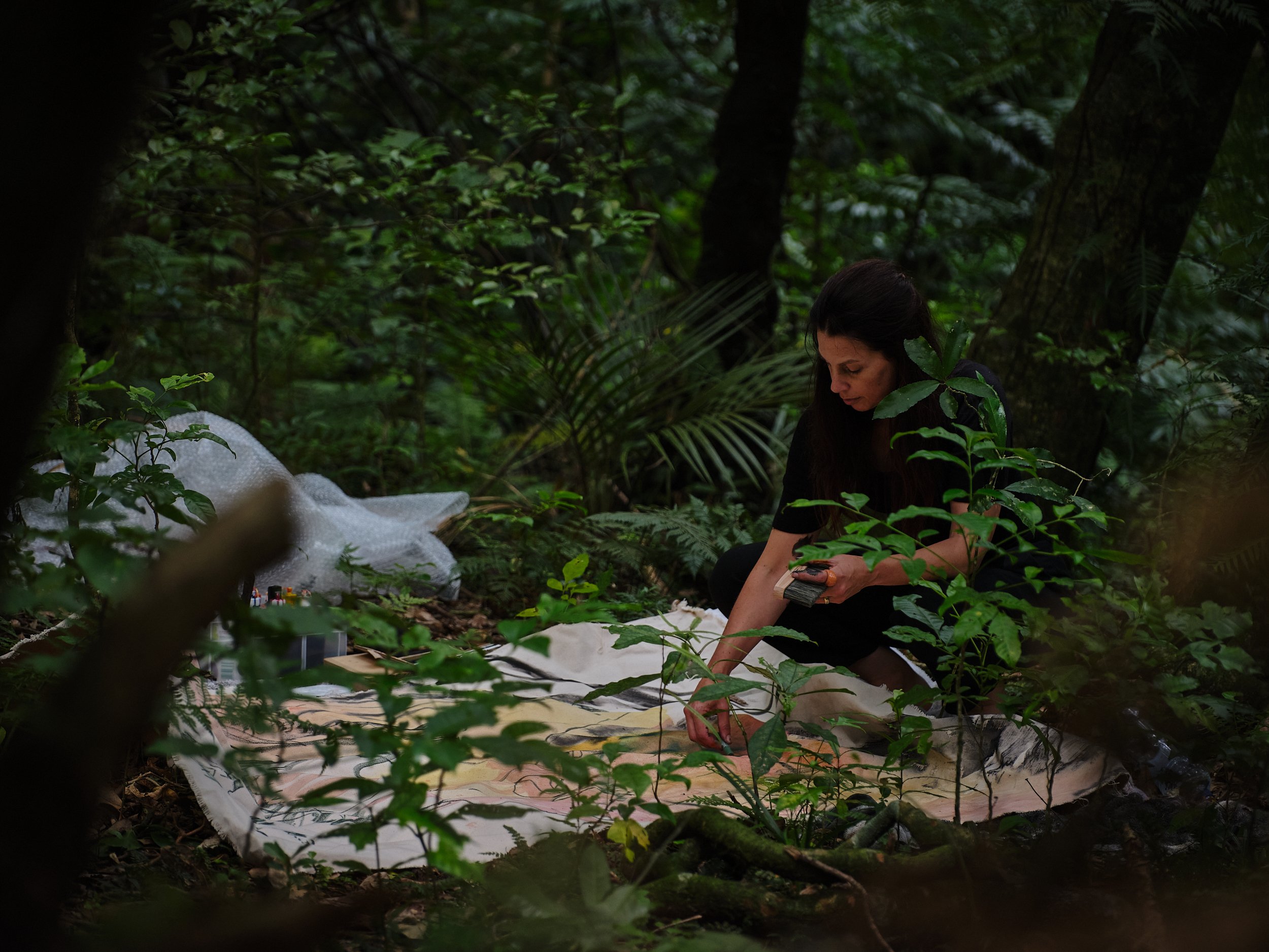 Artist Amanda Watson painting in the forest, en plein air, environment, performance art, new zealand women artist, artist who paintings outside wrapping trees