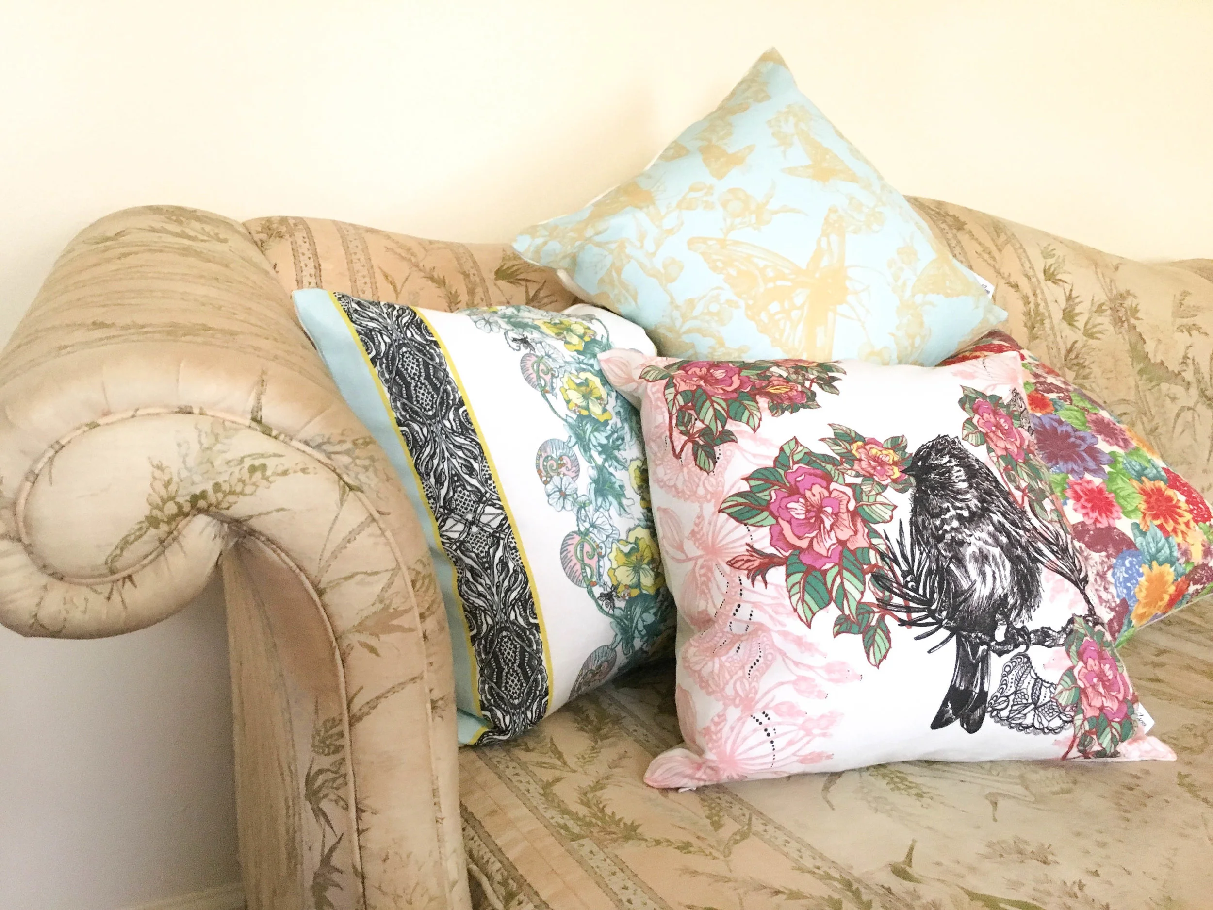 Acanthis Pillow, Cynthia Pillow, and Celandine Pillow piled on edge of a couch