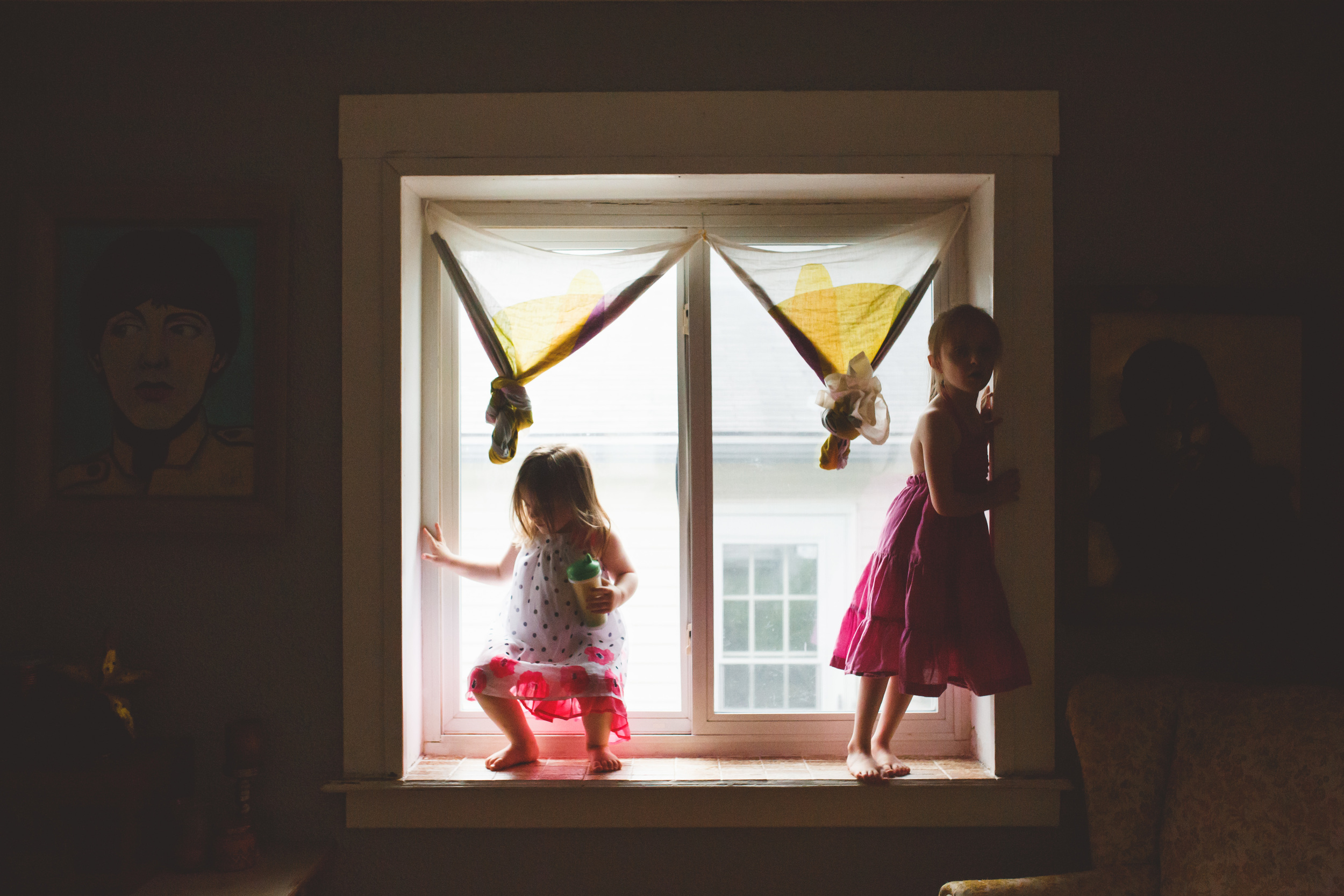 Two girls standing in a window.