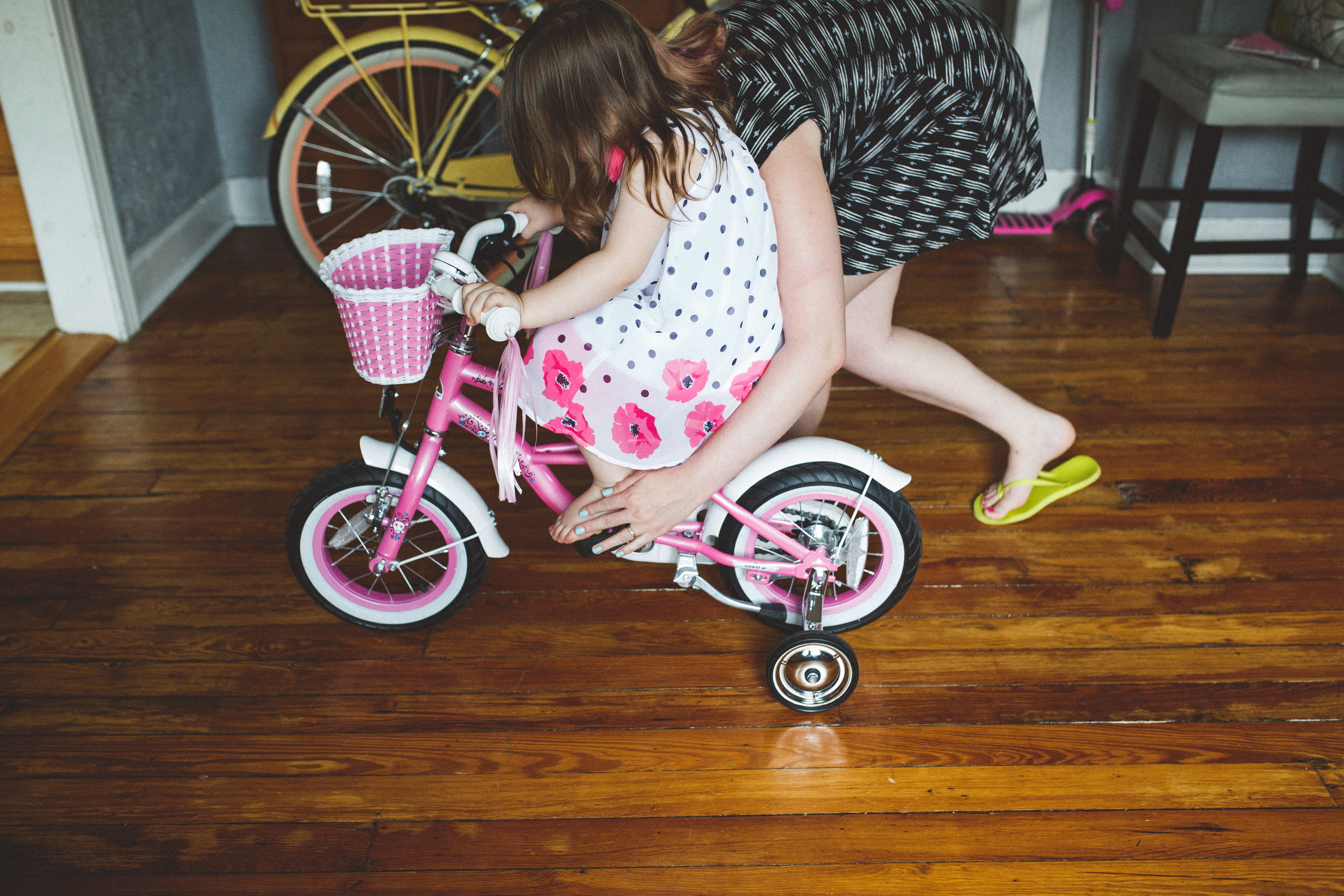 Mom helping daughter learn to ride bike.