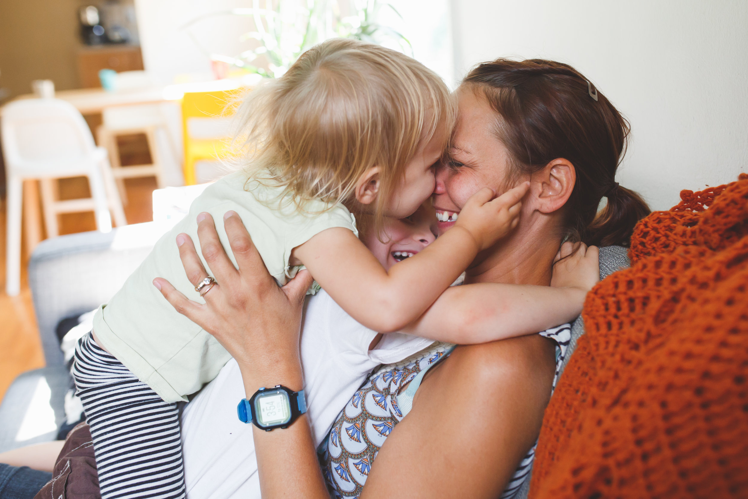 Kids hugging mom on couch.