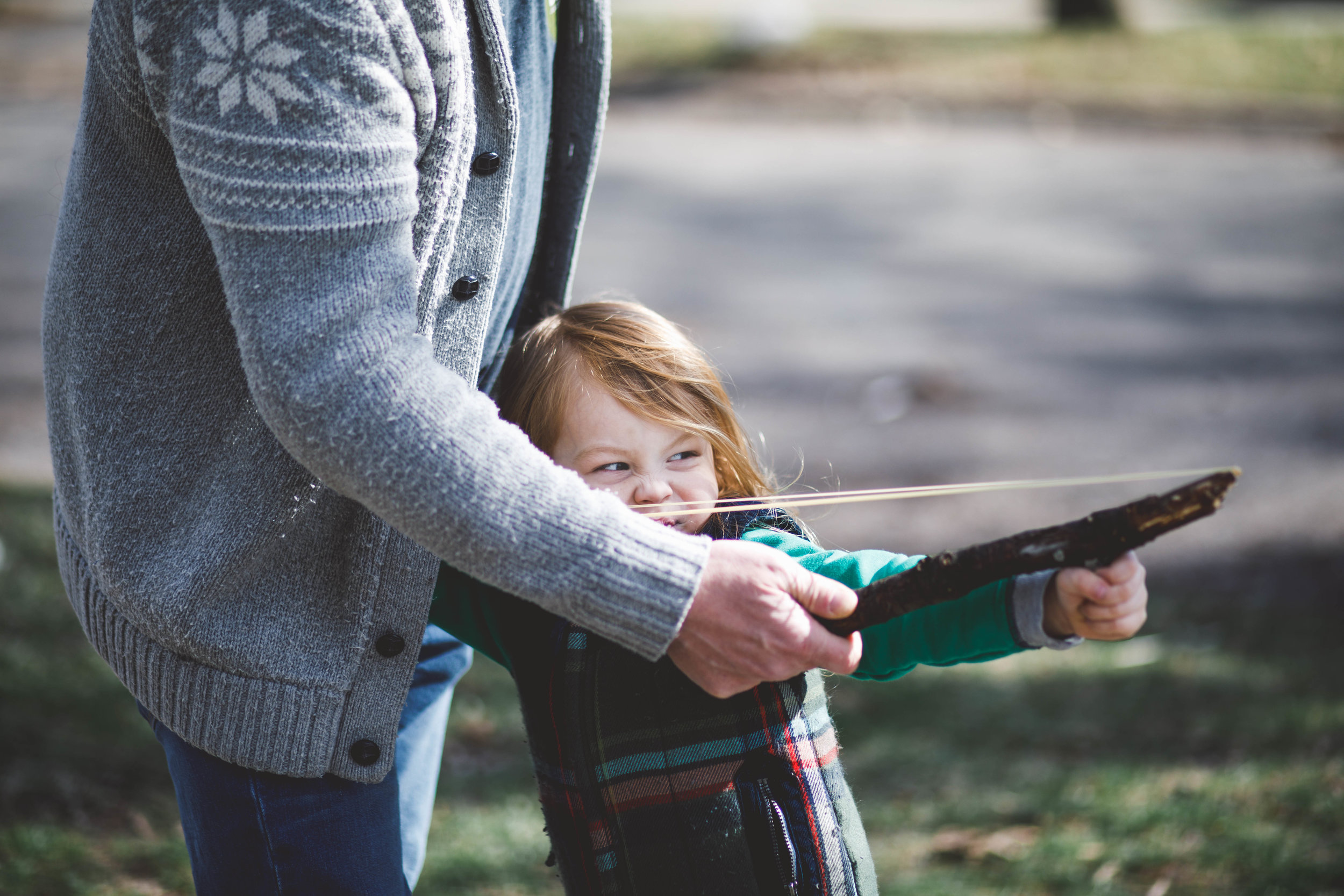 Little boy shooting rubber bands with dad.