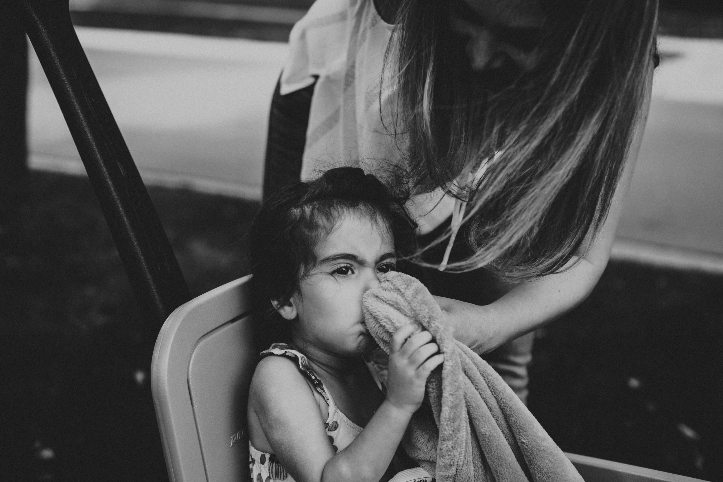 Mom wiping daughters nose with blanket.