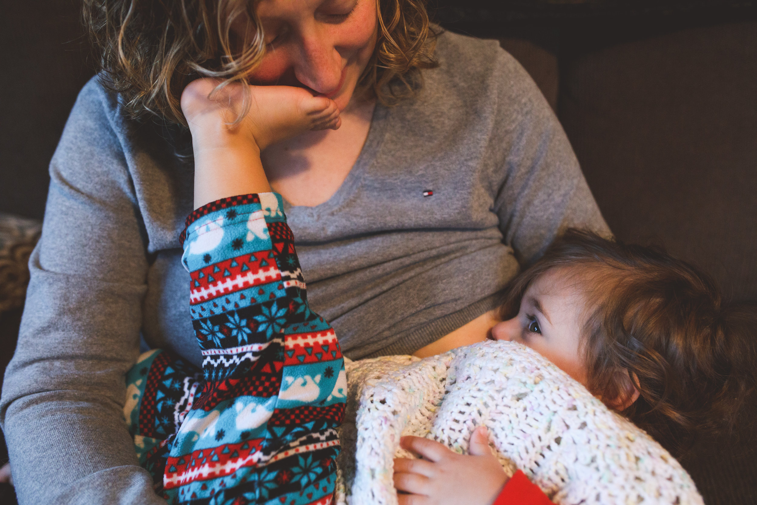 Nursing mom with daughters foot in her face. Ferndale Family Photographer. Royal Oak Family Photographer