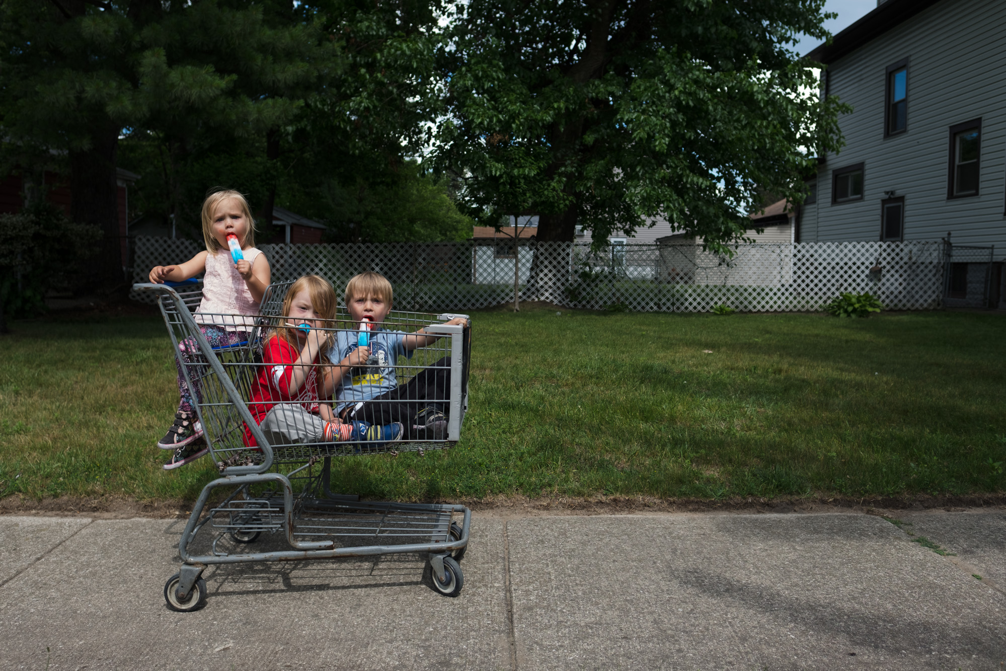 Kids eating popsicle in shopping cart.