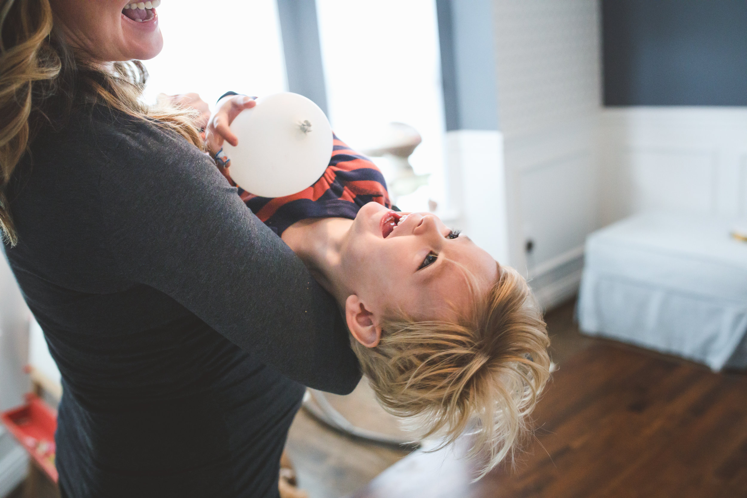 Mom holding happy boy with balloon.