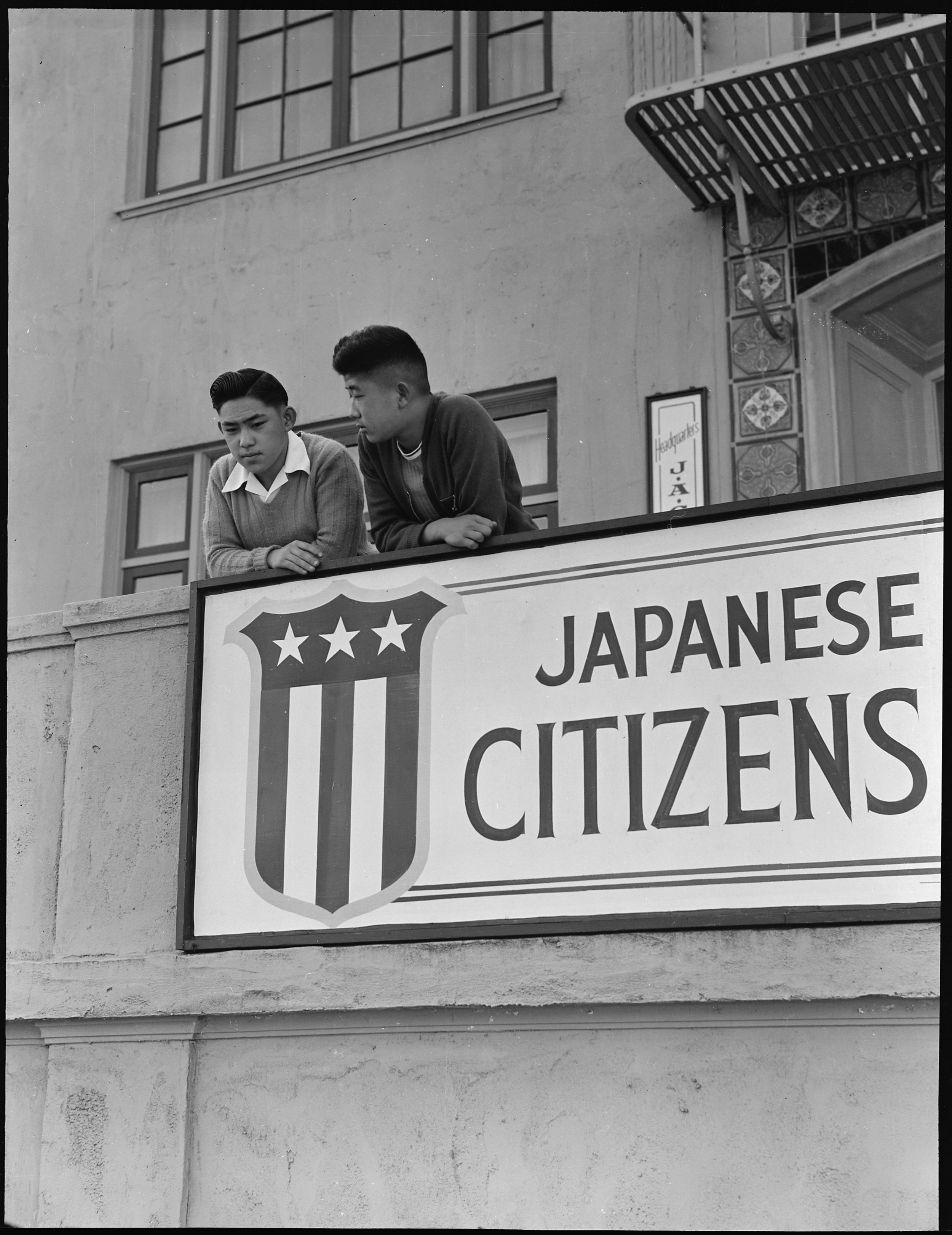    PRINT AVAILABLE   San Francisco, California. High school boys, on balcony of Japanese American Citizens League at 2031 Bush Street, look down sidewalk where friends boarded evacuation buses. Evacuees of Japanese ancestry will be housed in War Relo