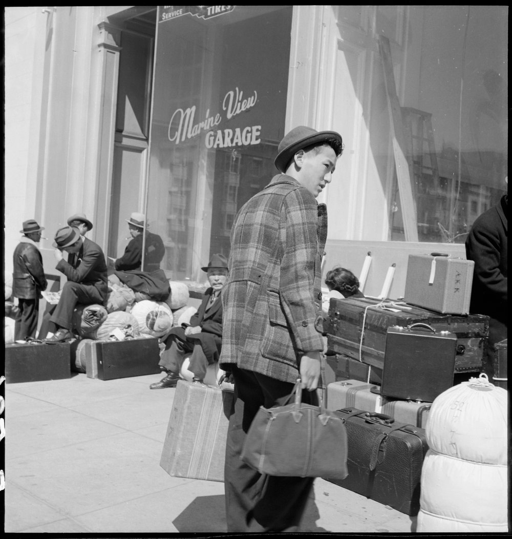  San Francisco, California. A young evacuee arrives at 2020 Van Ness Avenue, meeting place of first contingent to be removed from San Francisco to Santa Anita Park Assembly center at Arcadia, California. Evacuees will be transferred to War Relocation