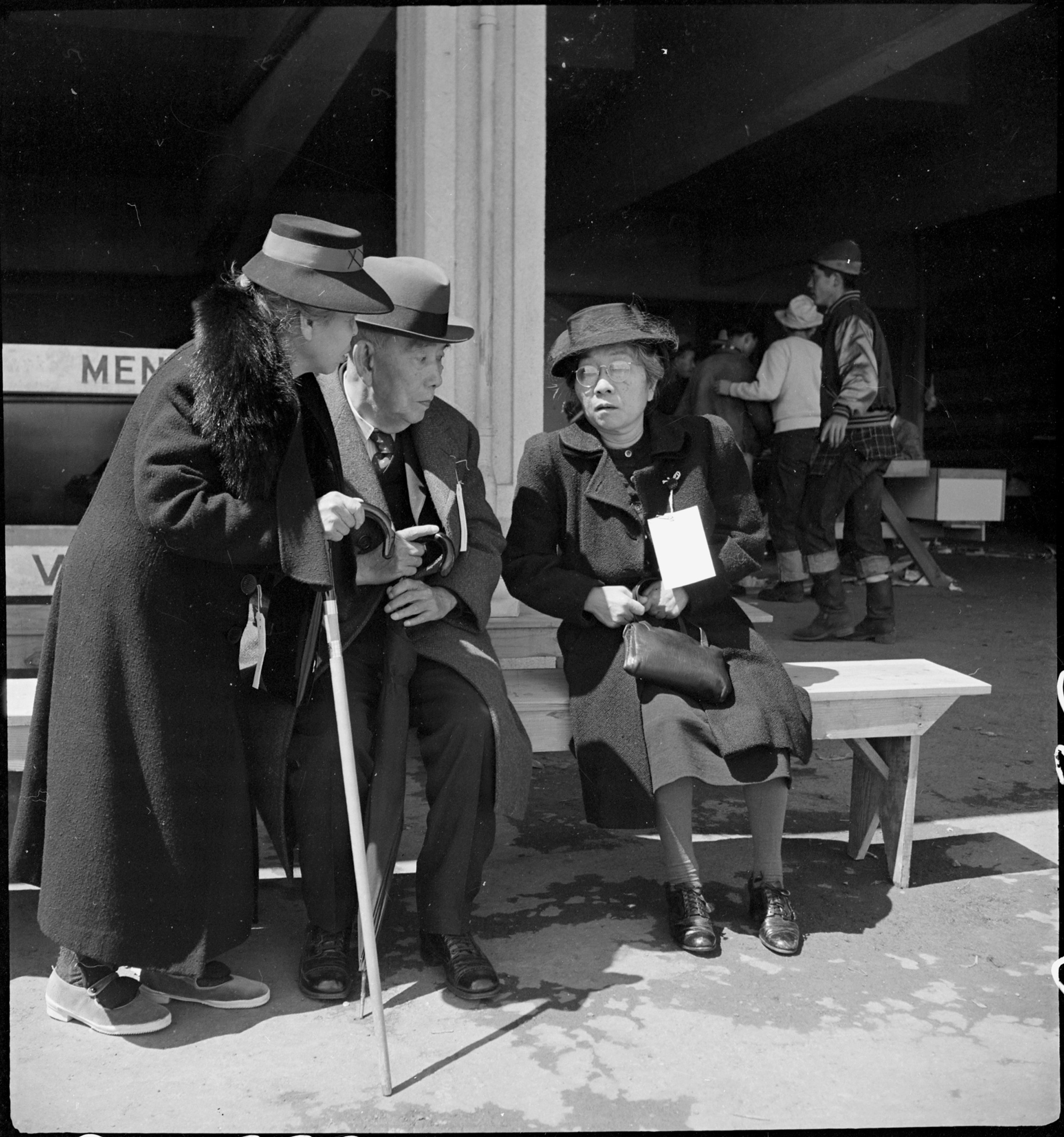  San Bruno, Caliofnira. These older evacuees of Japanese ancestry have just been registered and are resting before being assigned to their living quarters in the barracks. The large tag worn by the woman on the right indicates special consideration f