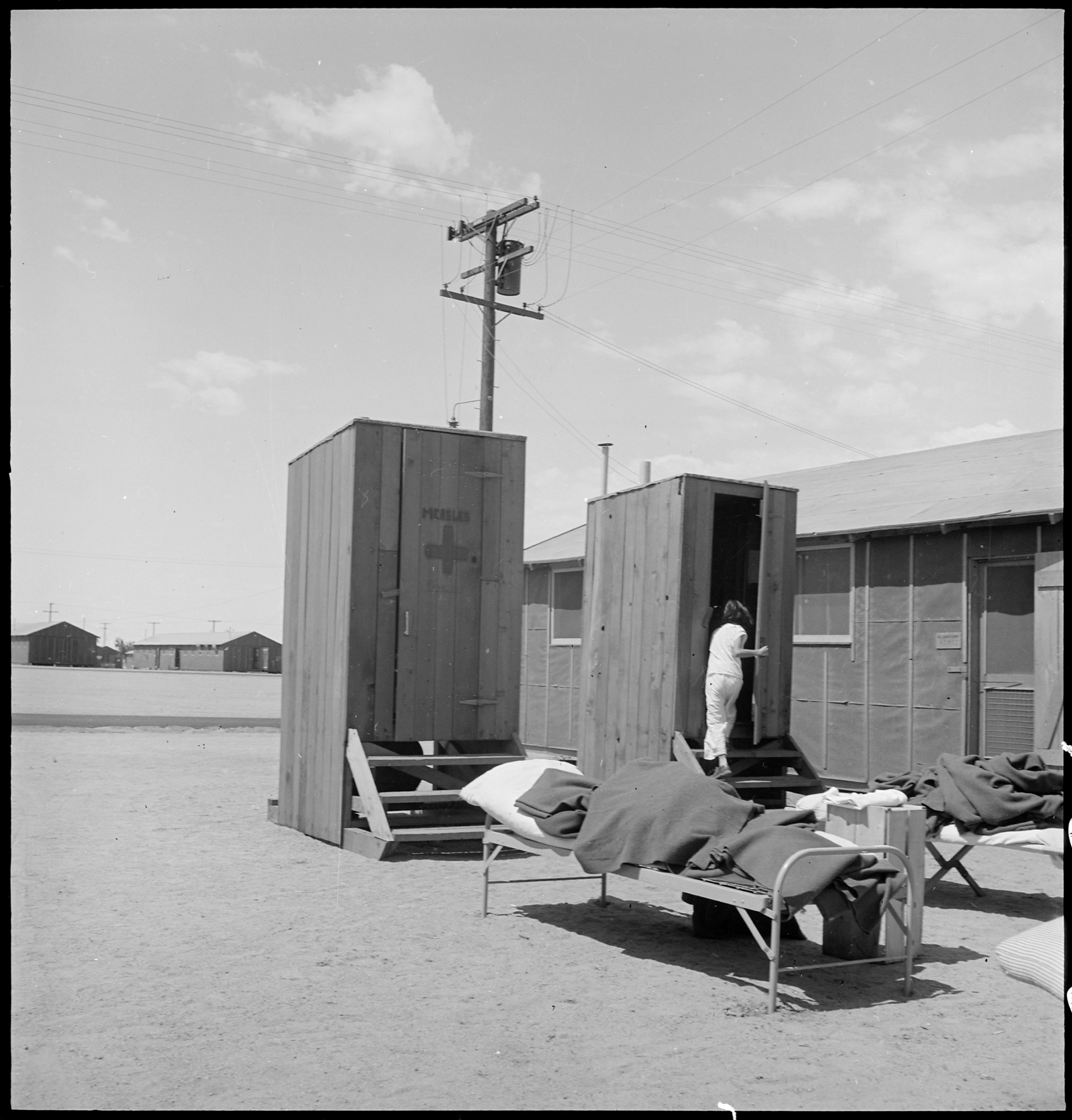 Manzanar Relocation Center, Manzanar, California. Hospital latrines, for patients, between the barr . . .