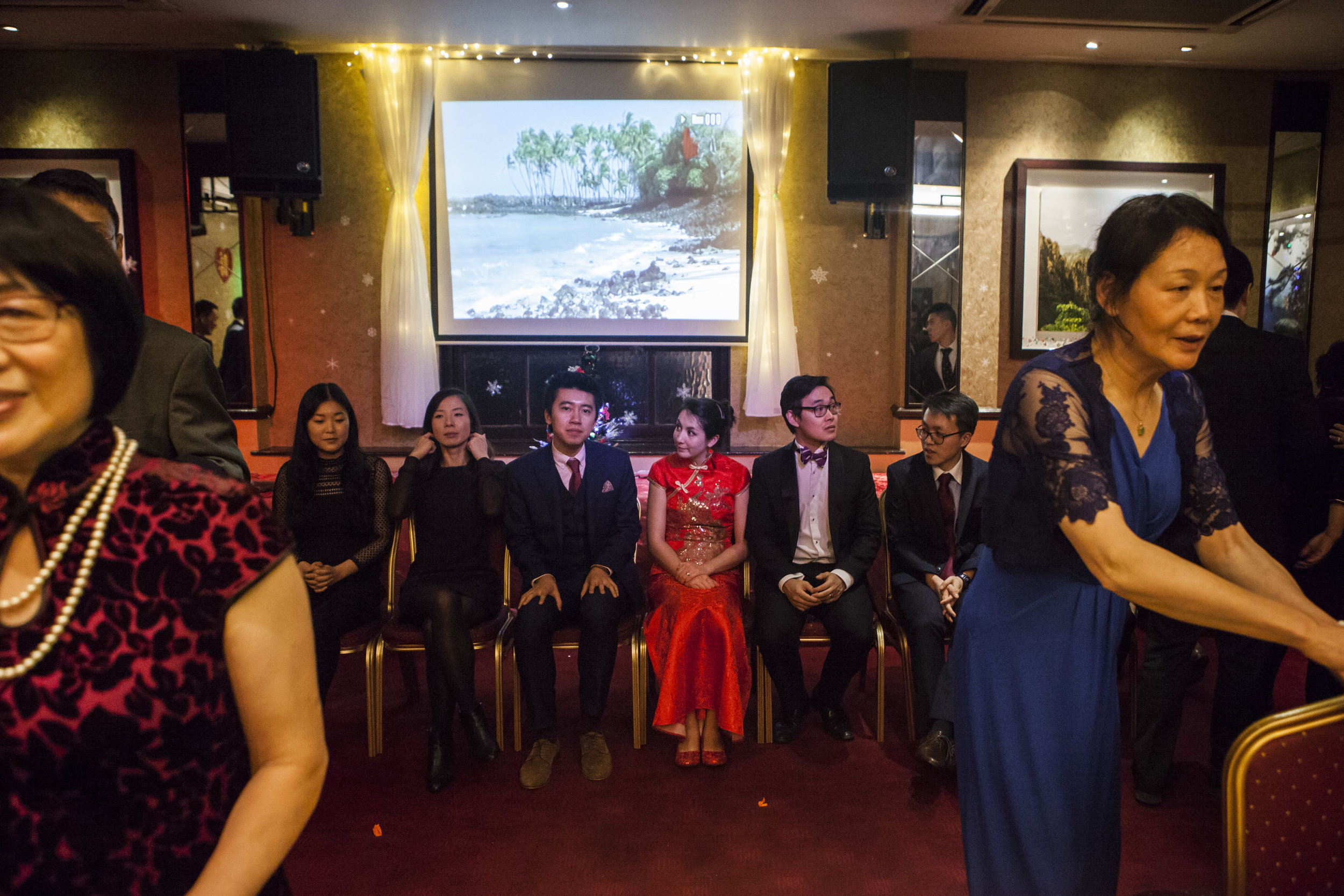  Second generation Chinese migrants sit with the bride and groom on stage while the parents prepare the venue for the next event.&nbsp; 