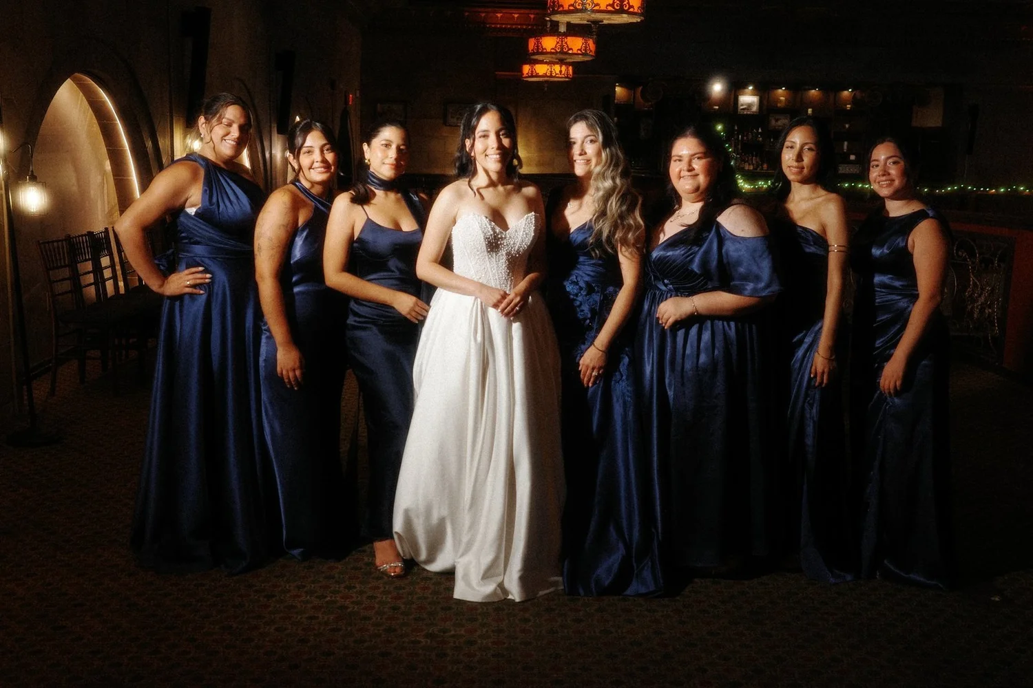 The Society Room of Hartford wedding photographer, Hartford, CT â€” bride and bridesmaids in navy satin beneath the arched windows of the ballroom