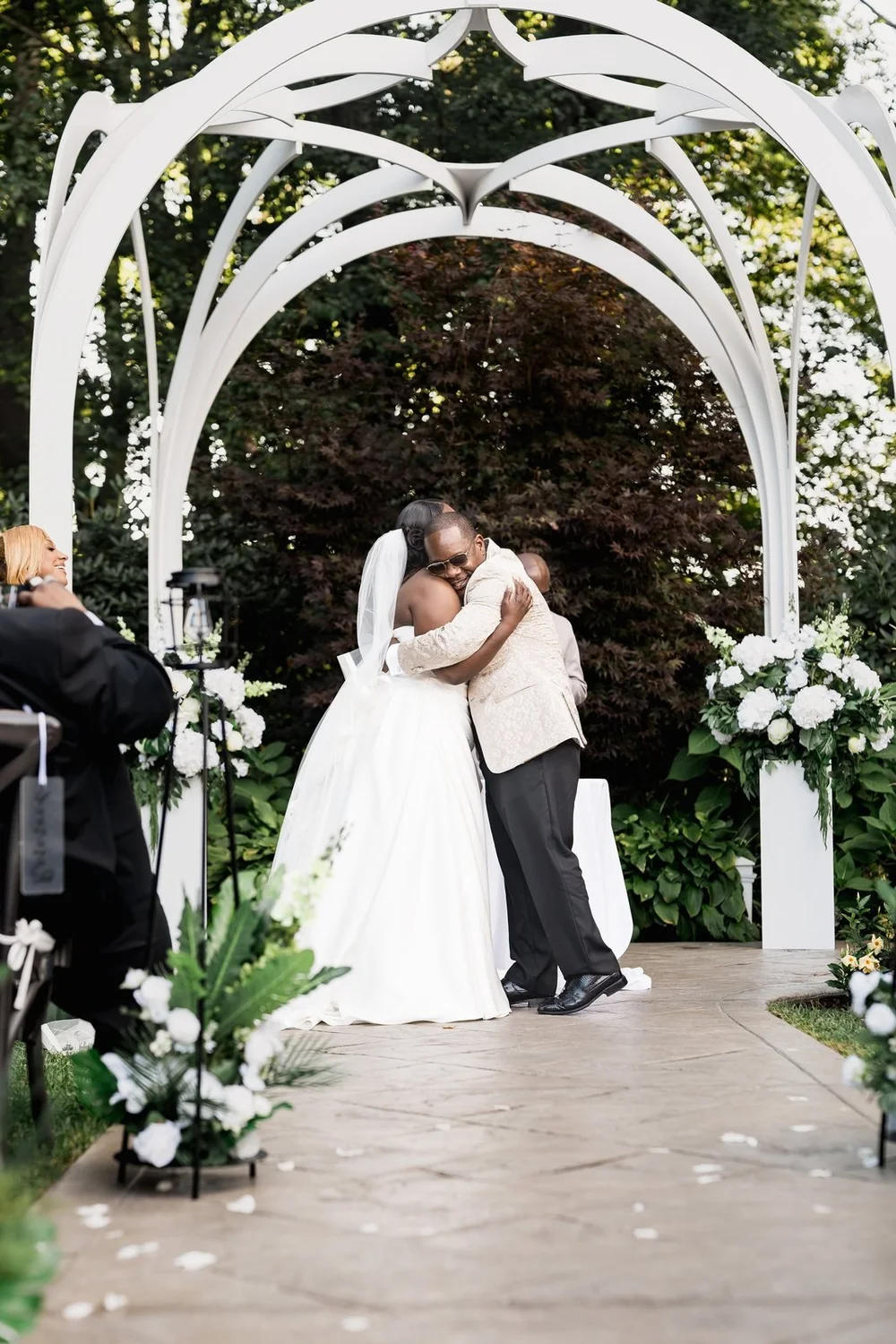 Avenir wedding photographer, Walpole, MA — first kiss beneath the white garden arbor
