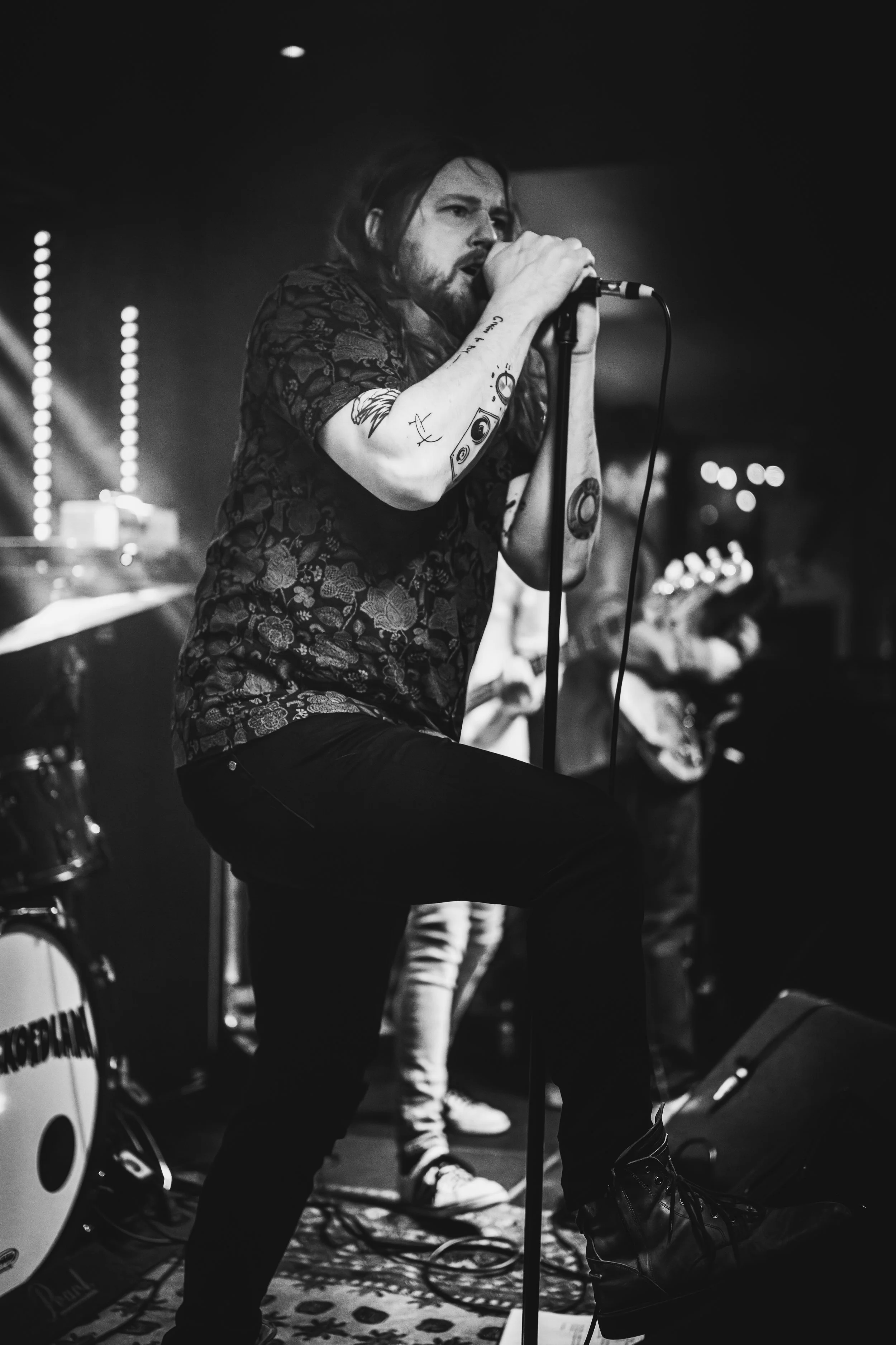 Tobias Carleke singing on stage with a microphone during a live performance
