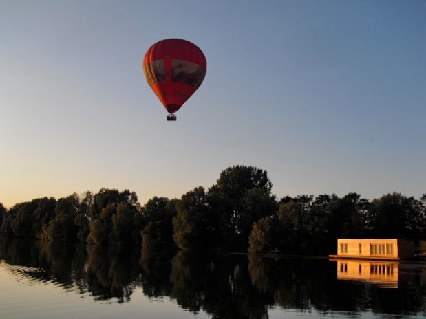 A hot air balloon drifts over an Oxfordshire Lake