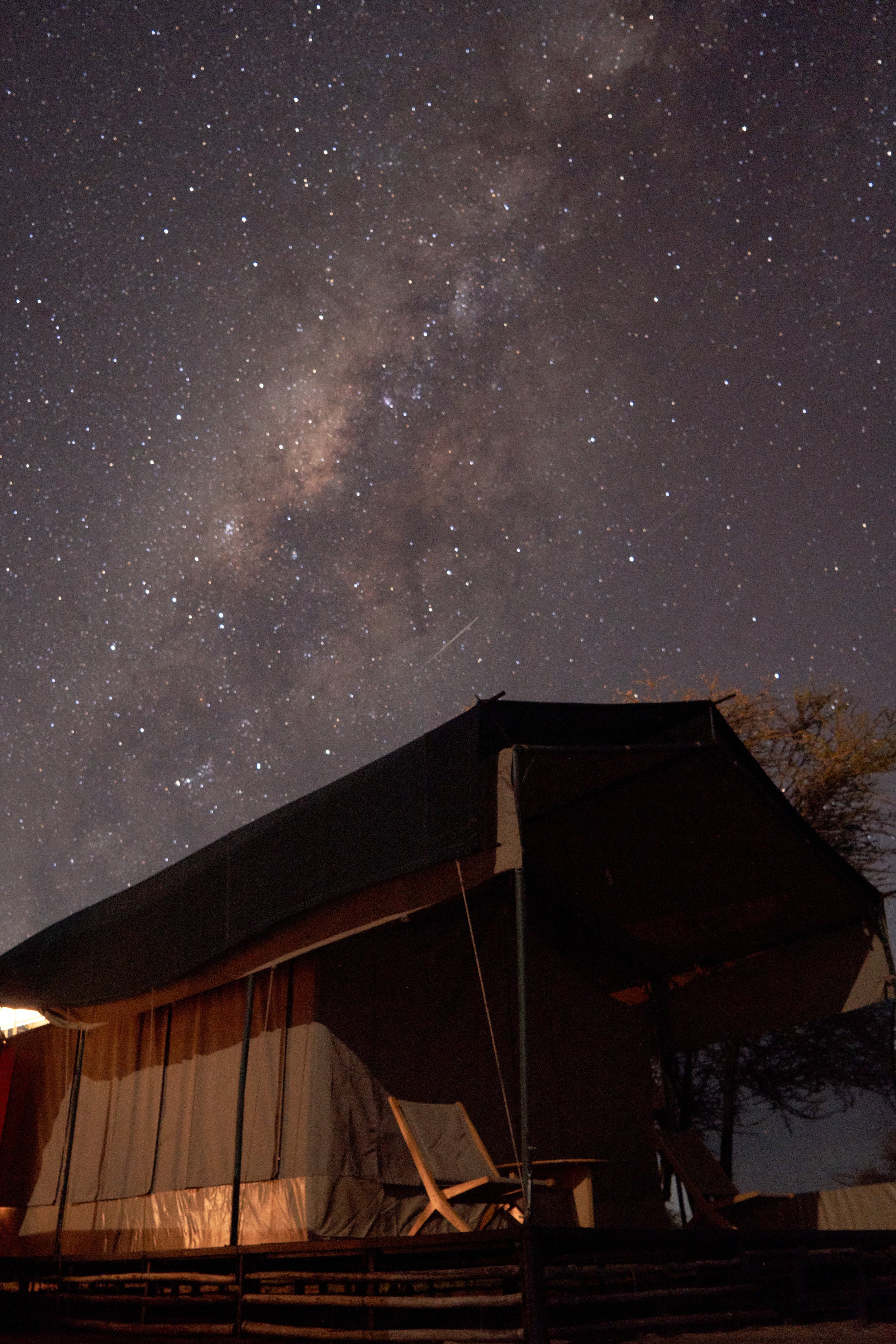 Night sky filled with stars viewed between two dark objects with orange and black fabric sides.