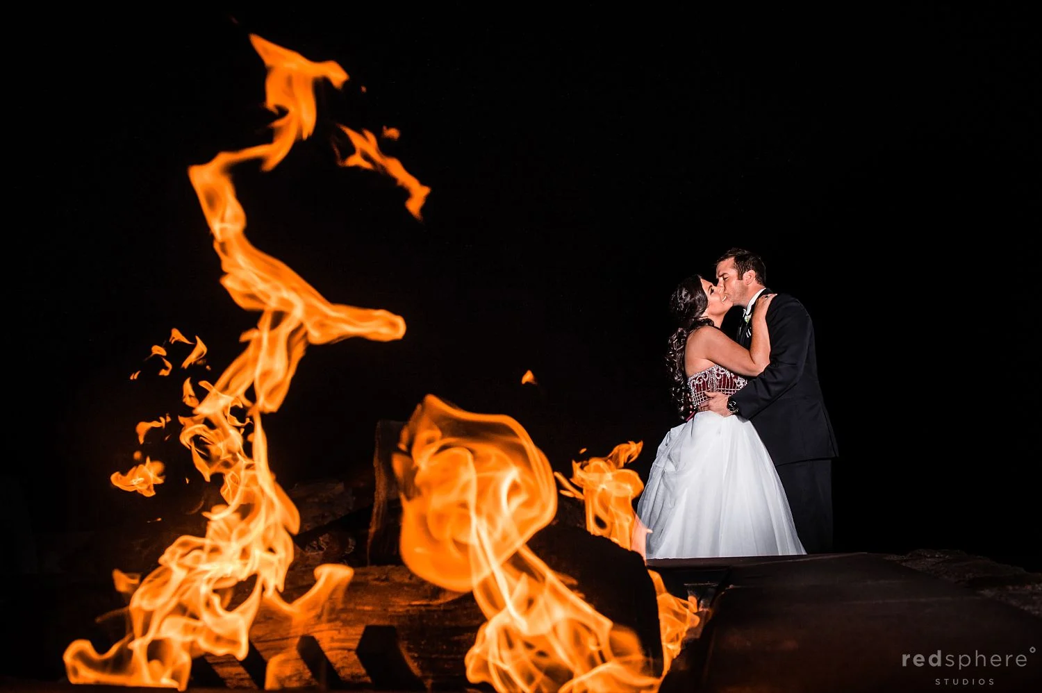 Bride and Groom Kiss Next to a Fireplace