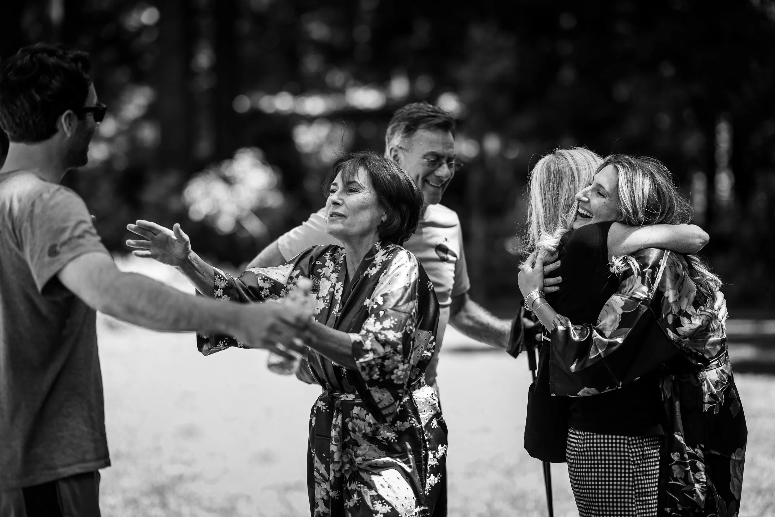 People sharing joyful hugs and conversation outdoors.