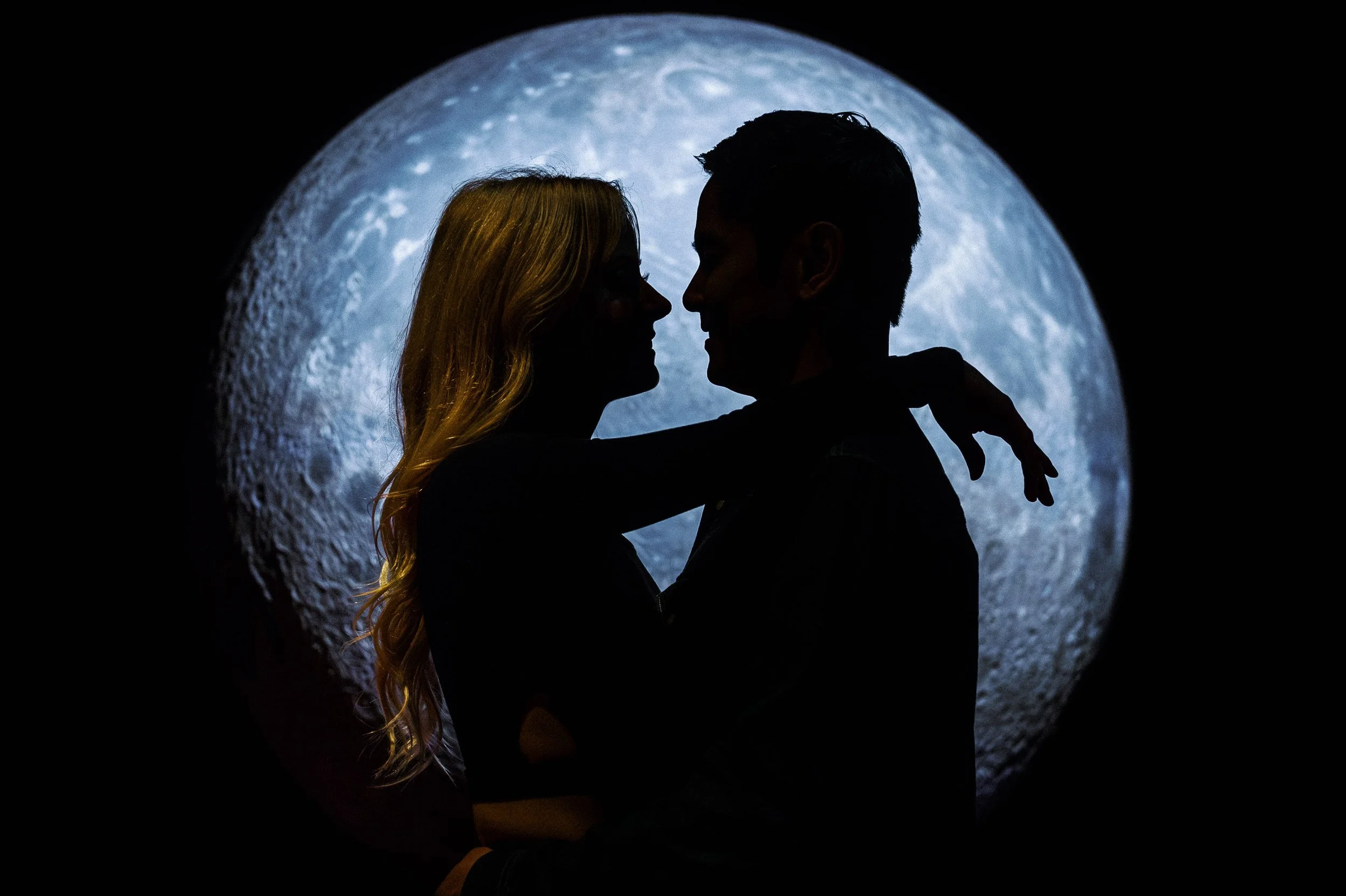 Silhouetted couple embracing with full moon in the background. Engagement session at the Griffith Observatory in Los Angeles.
