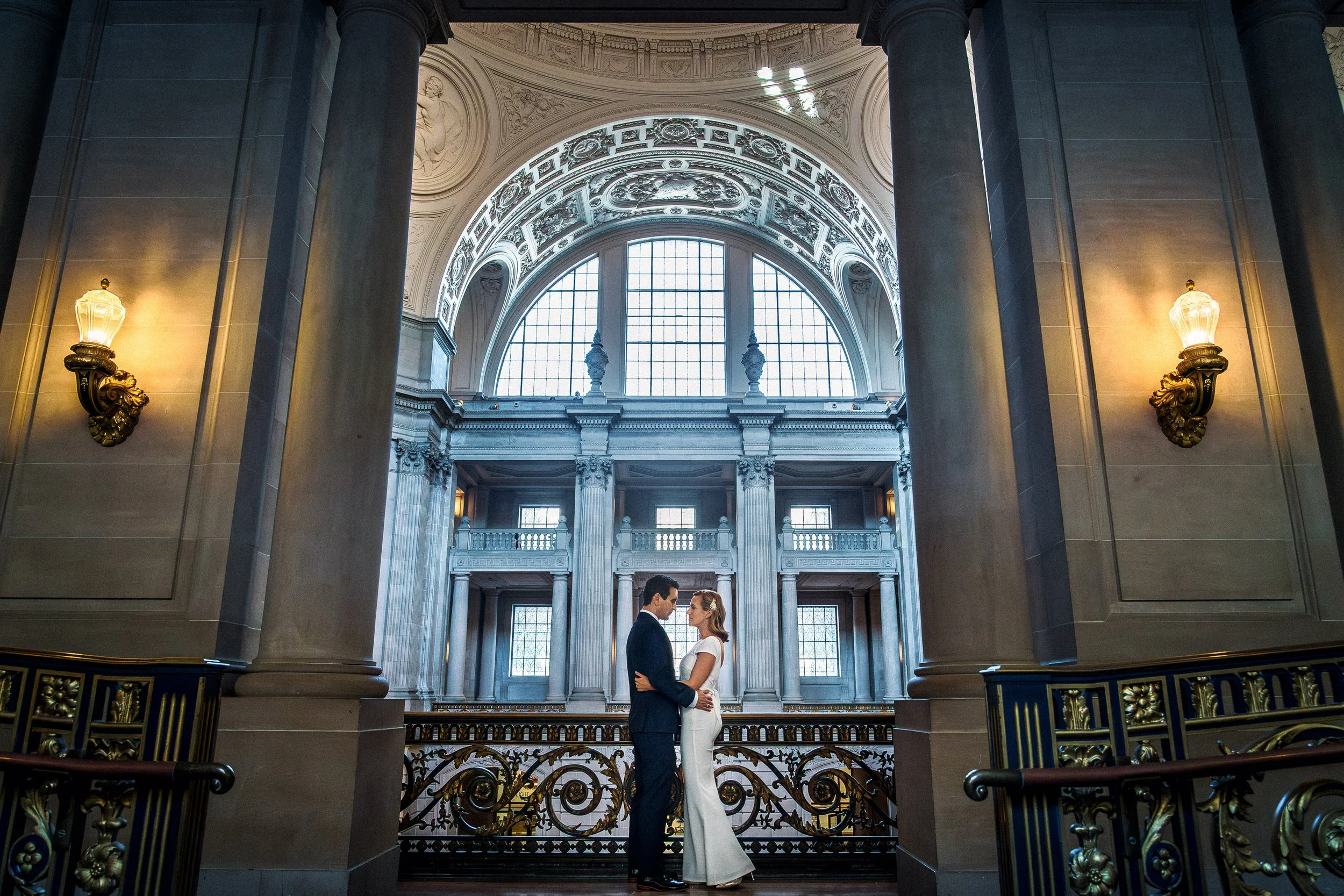 A couple standing close together and gazing into each other's eyes inside San Francisco City Hall.