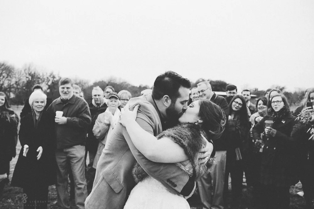 Bride and groom kissing in front of guests at ceremony