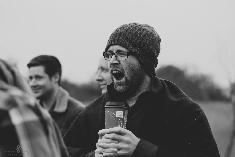 Man yawning while holding a cup of coffee
