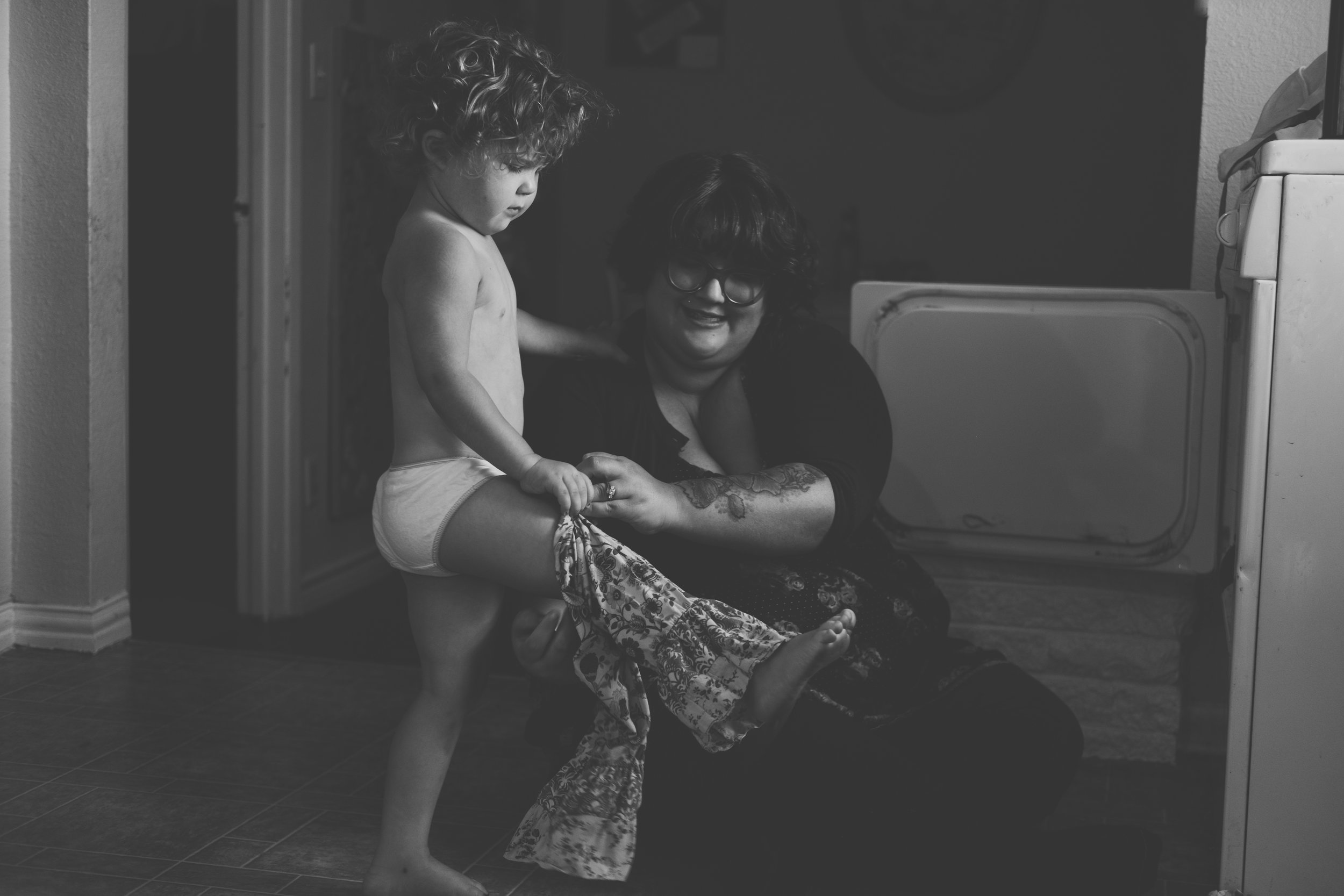 Mother helping daughter put on pants