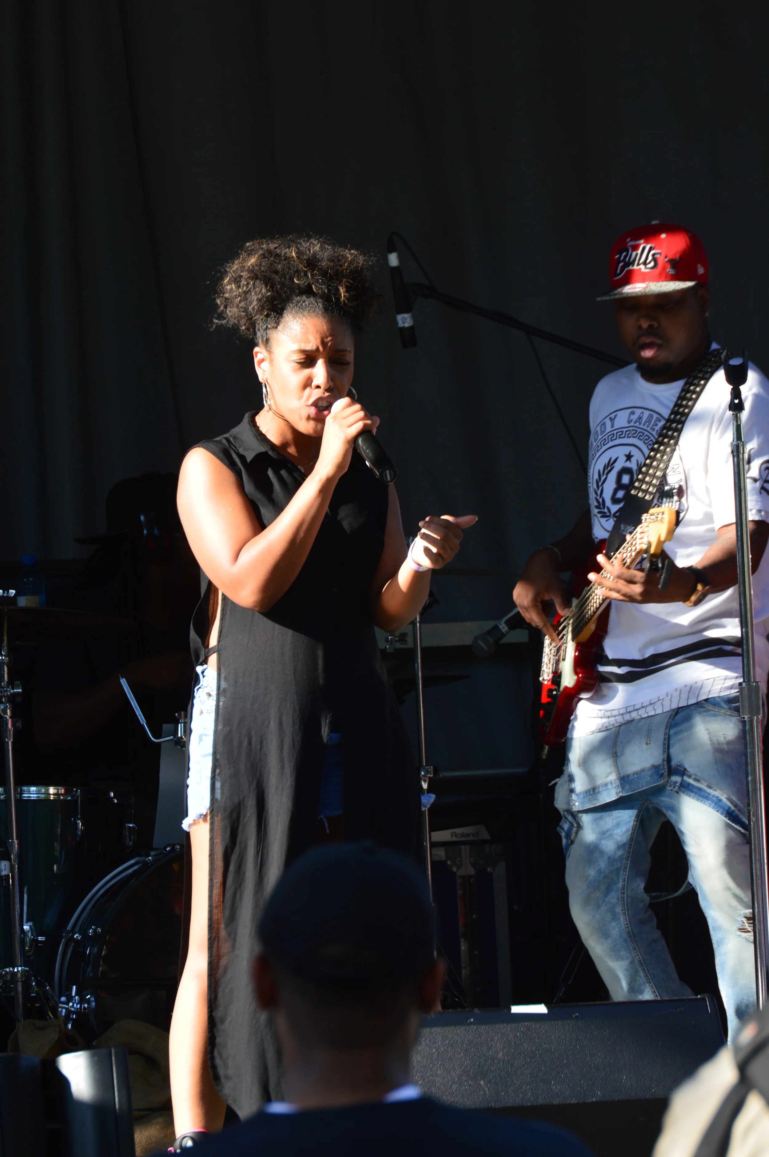 A woman singing into a microphone and a man playing a guitar perform on stage during a concert.