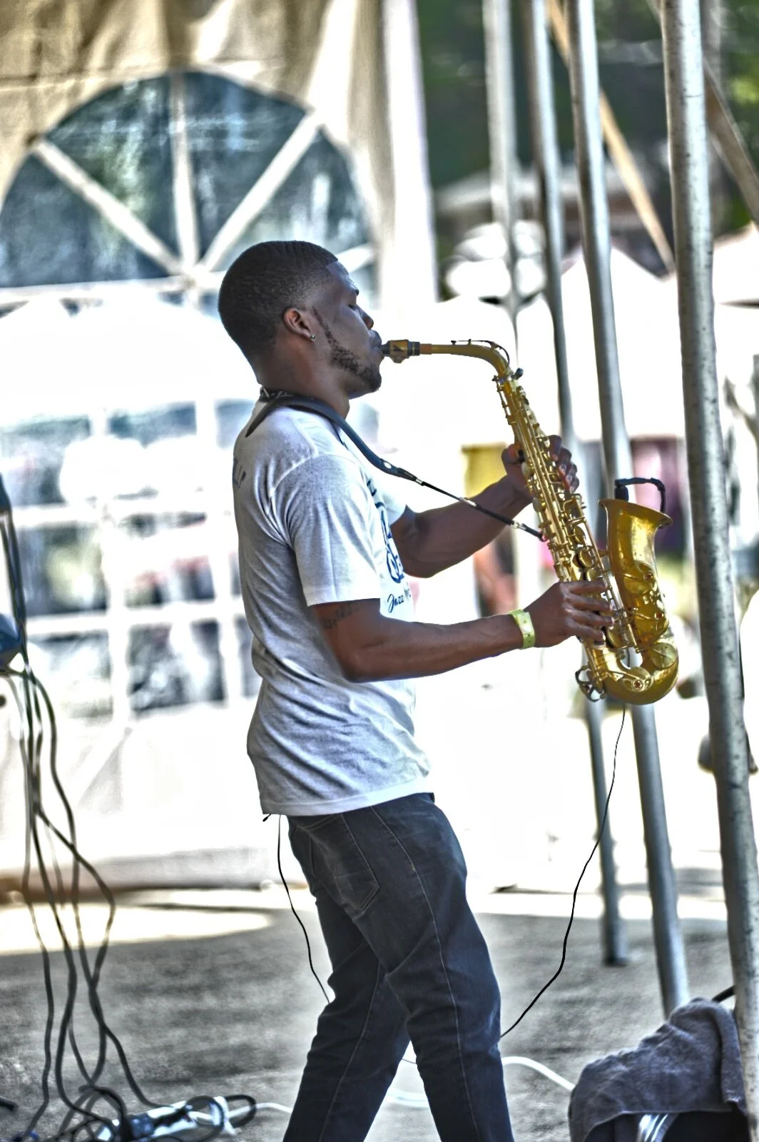 A man playing the saxophone on stage at an outdoor event.