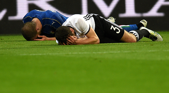 Germany's Hector (R) and Italy's Insigne (L) are shown laying on the ground after a clash. (Photo by PATRIK STOLLARZ/AFP/Getty Images)
