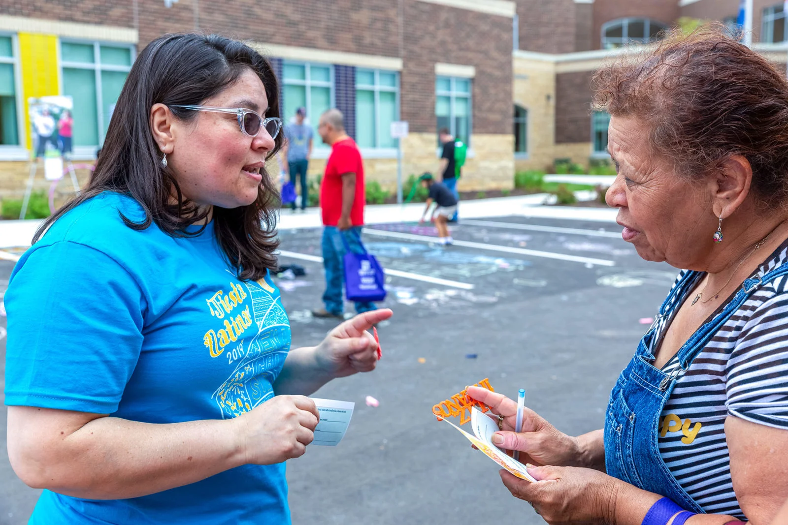 Marylu Ramirez (L) chats with a community member at the Fiesta Latina at Comunidades Latinas Unidas en Servicio (CLUES) in St. Paul's East Side on Aug. 10, 2019. Photo courtesy Kerem Yucel for MPR News