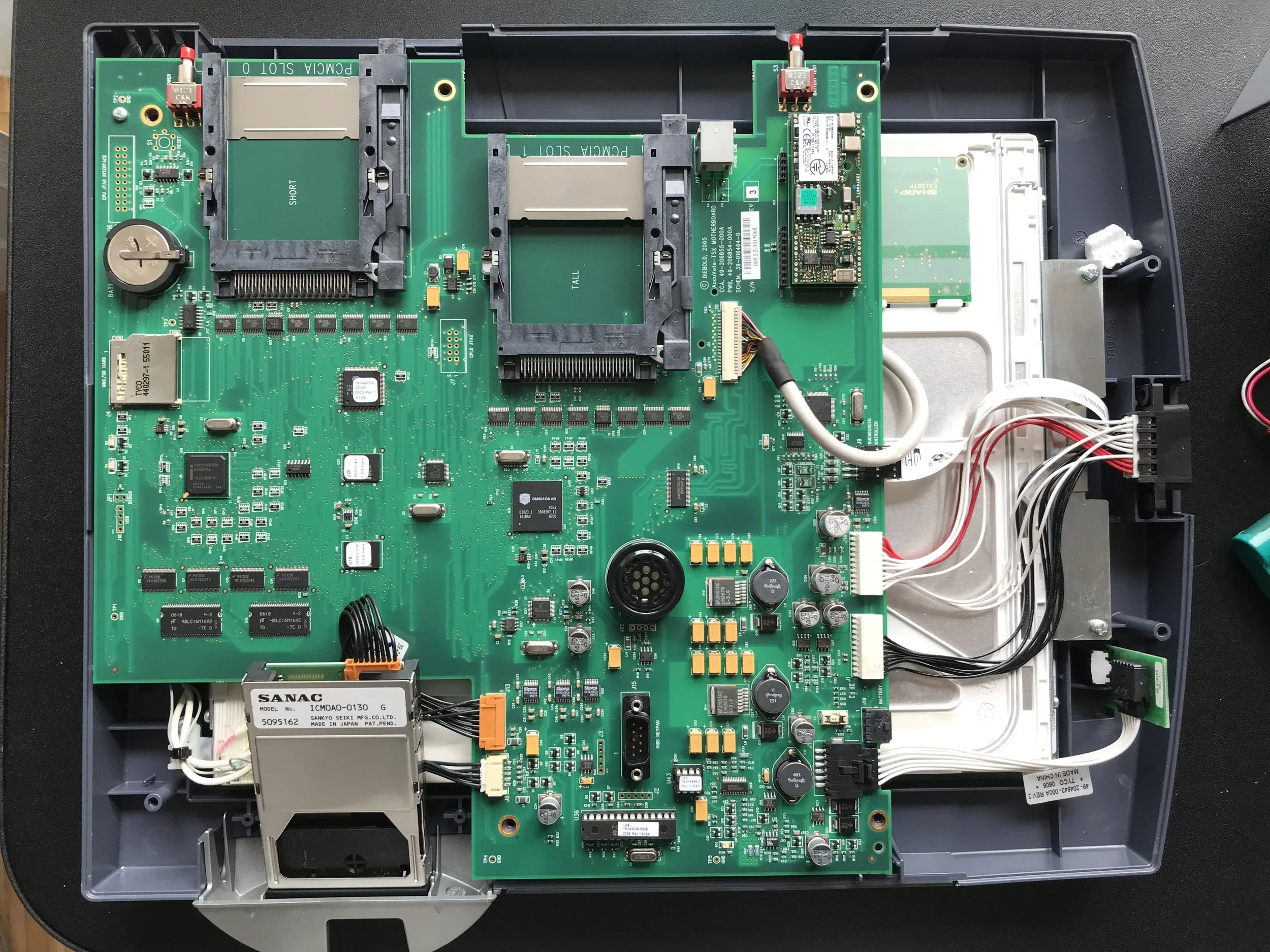 Figure 2: The victim, laid bare. Note the useful silkscreen all over the board, handy to figure out how the device is supposed to work. Also of note, every part is well-documented and broadly used, from the SM501 system controller, to the Intel PXA CPU, through to the touchscreen digitizer. Not one of these parts provides a real security model.