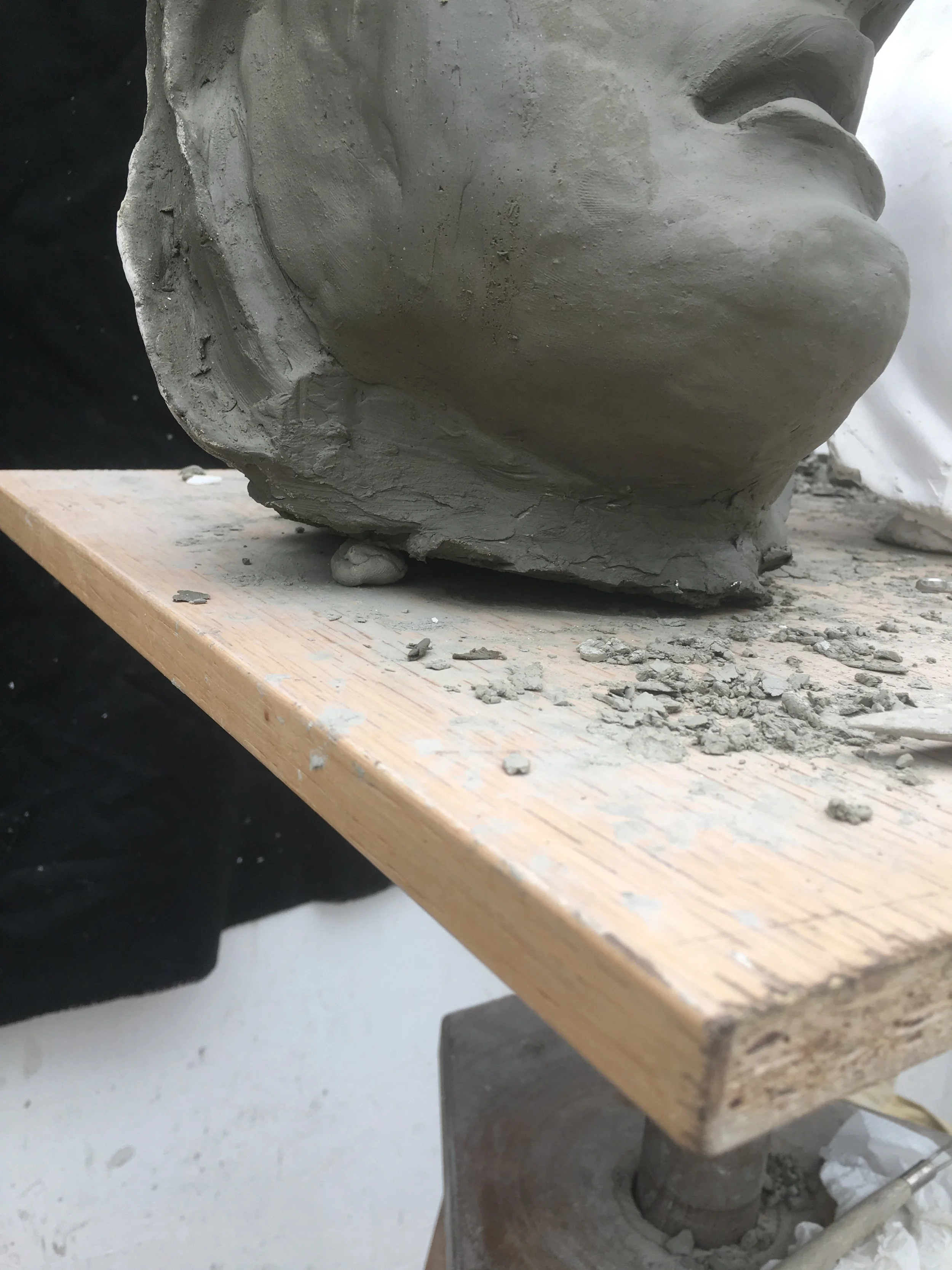 One method to fix a tilt in a clay sculpture is to take a dry clump of clay and wedge it into the area that needs to be raised. Then press fresh clay into the gap.