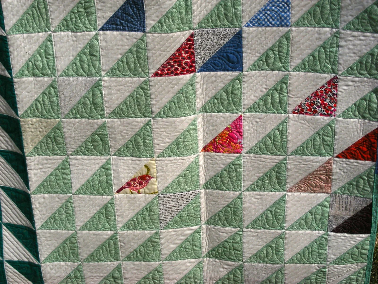 Patchwork quilt with triangle patterns in green, white, and various colors.