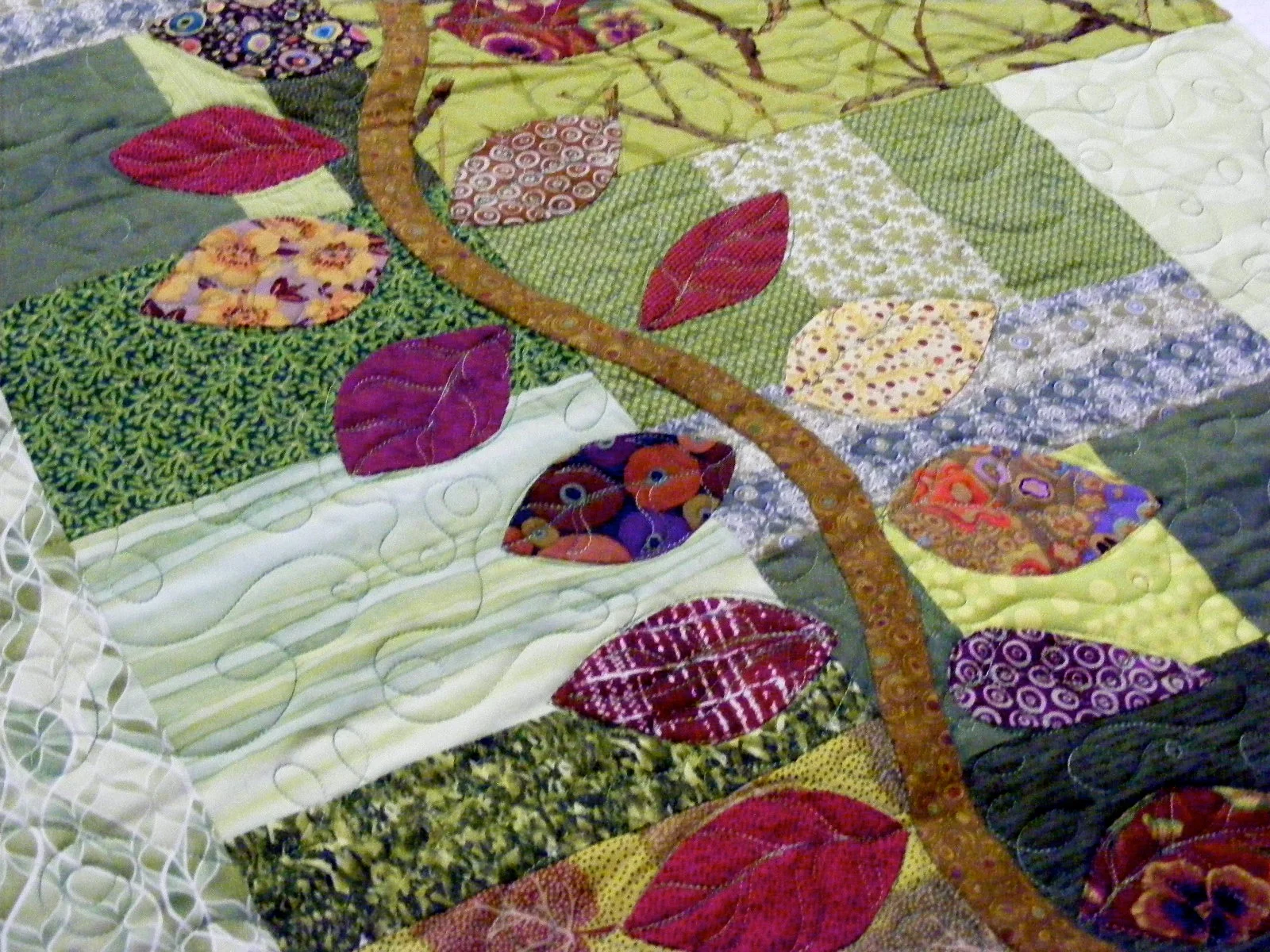 Patchwork quilt with leaf patterns and green tones