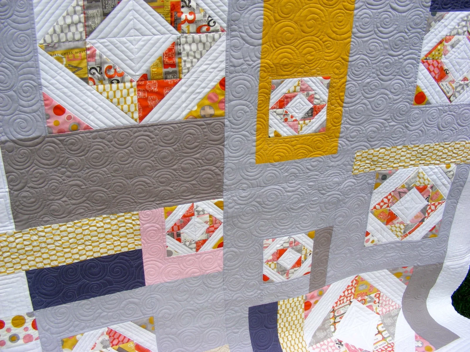 Colorful patchwork quilt with geometric patterns and swirl stitching