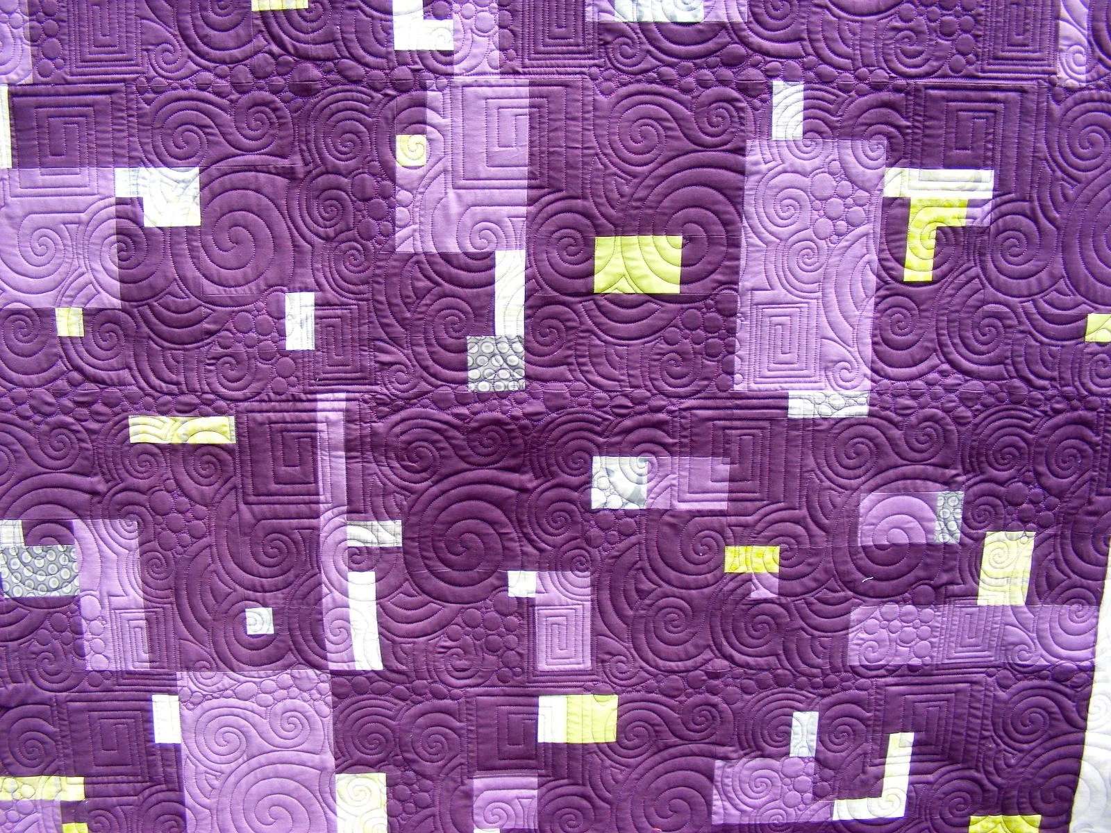 Purple quilt with geometric and swirl patterns