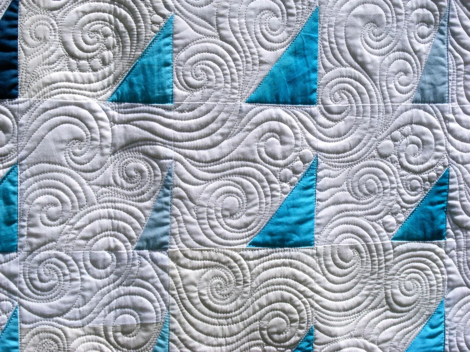 Quilt pattern with blue triangles and white swirls