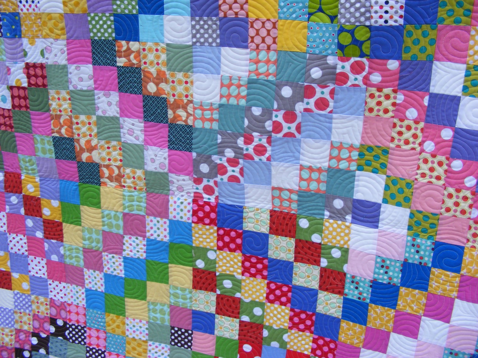 Colorful patchwork quilt with various patterned squares in a grid layout.