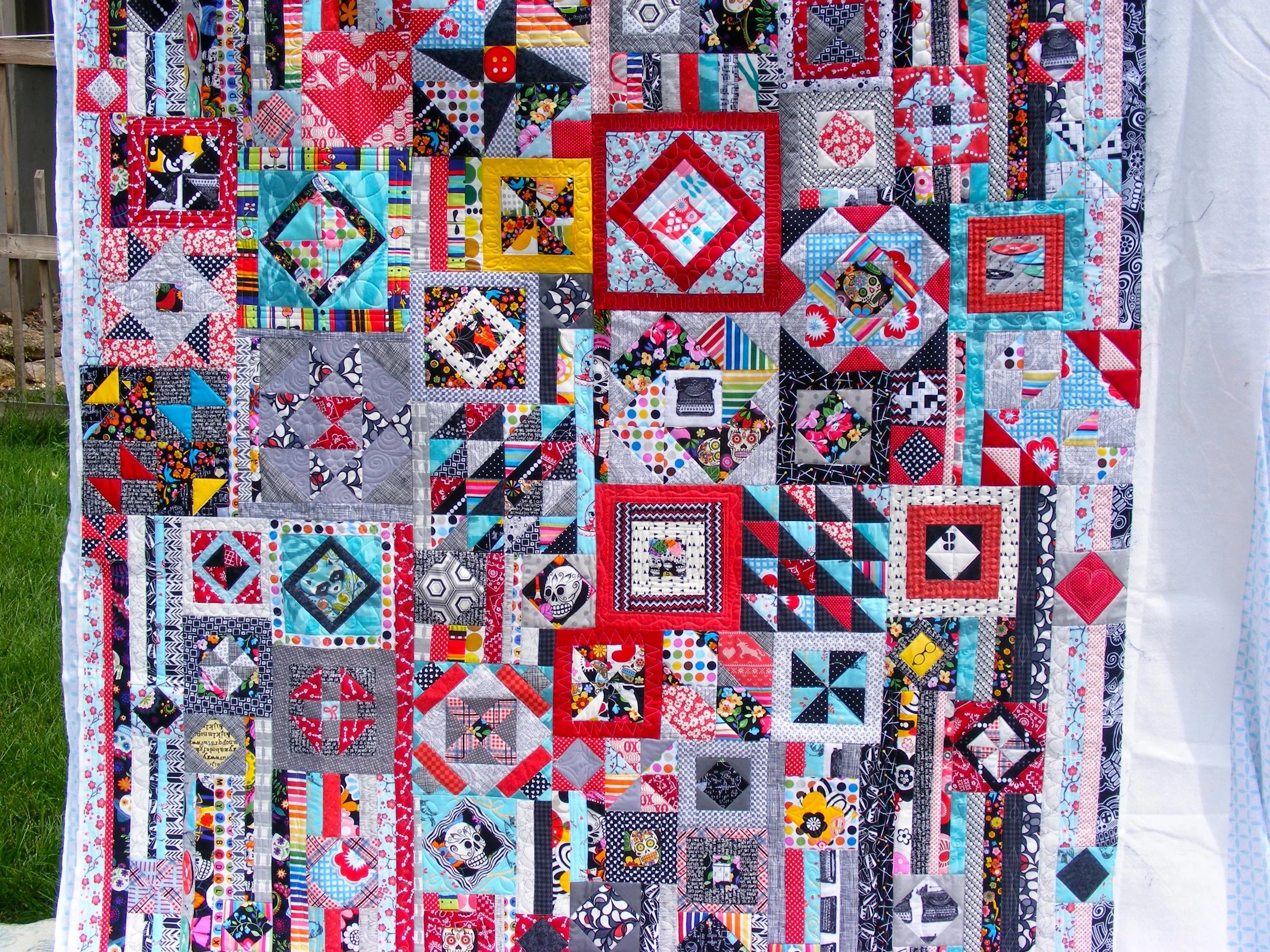 Colorful patchwork quilt with various geometric patterns and vibrant colors displayed outdoors.