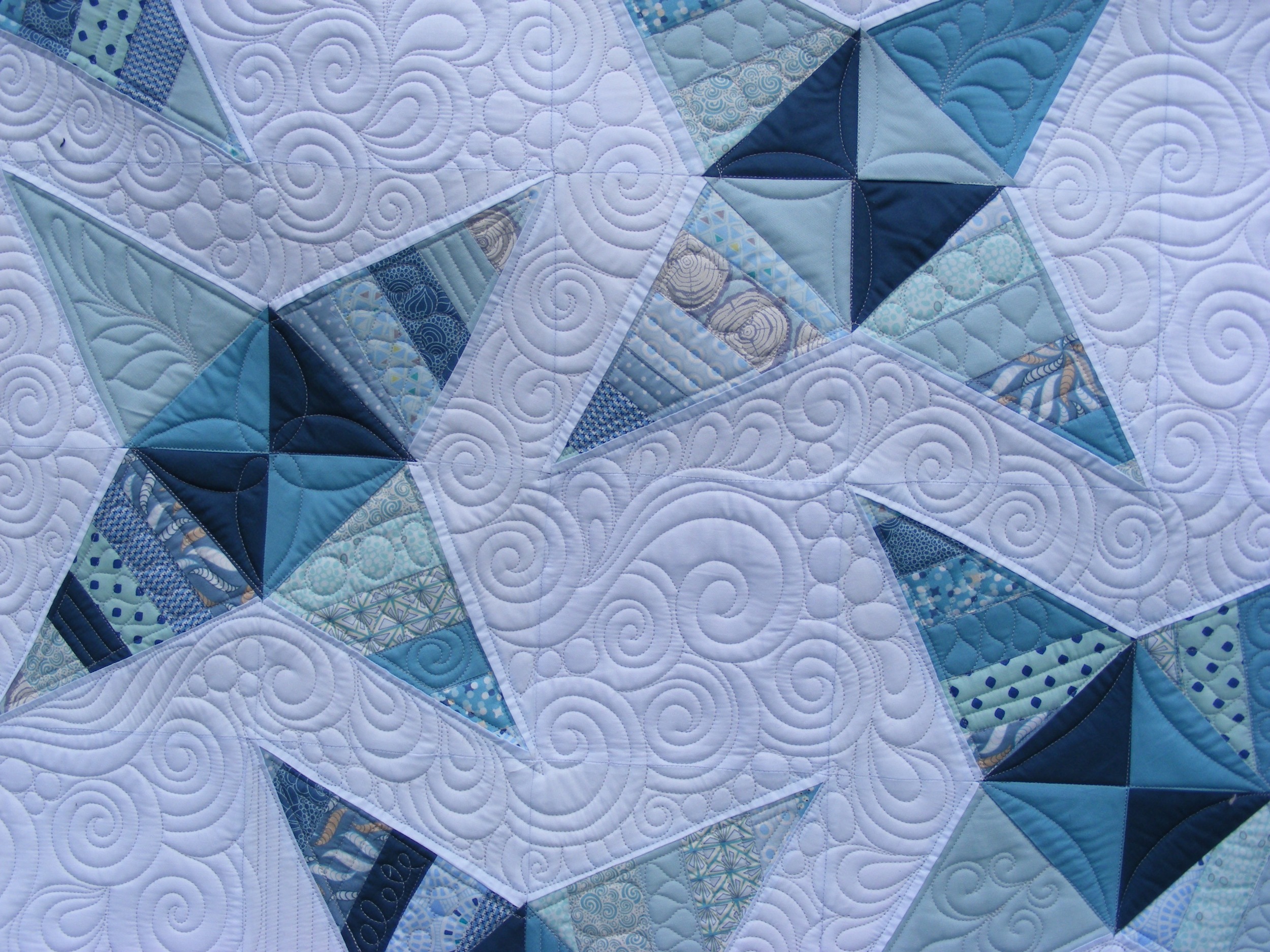 Blue and white star-patterned quilt with intricate swirl stitching.