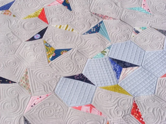 Quilt with geometric patterns and colorful triangle sections.