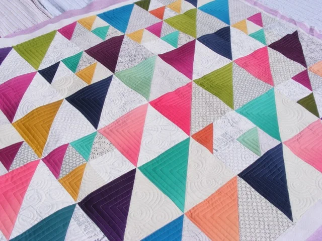 Colorful geometric quilt with triangular patches in various colors and patterns.