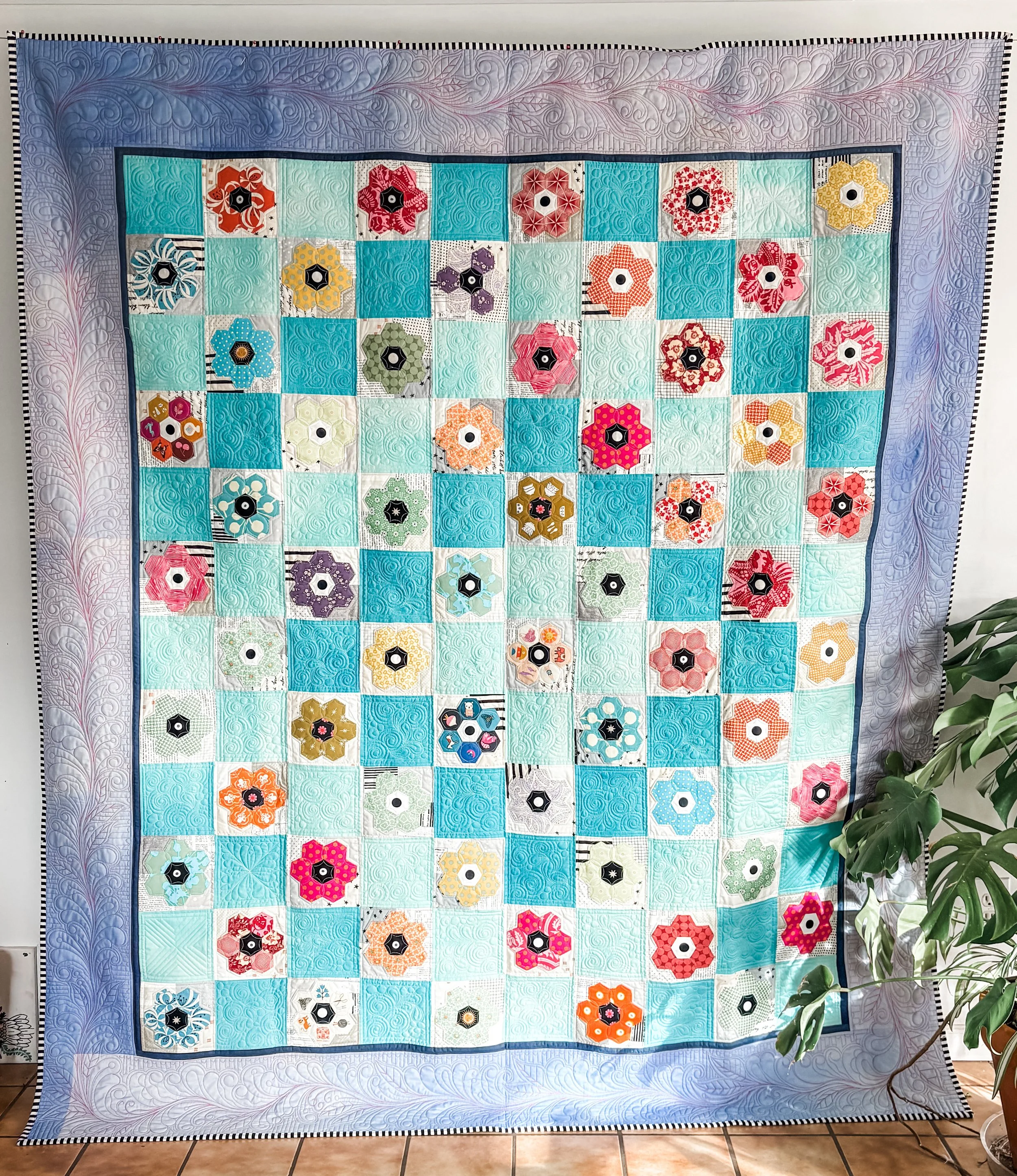 Juanita's Garden made by Tia Curtis. This is another English paper pieced quilt. I did not have the patience to make a traditional Grandmothers flower garden quilt, so I appliqué the blocks onto backgrounds and went from there. I custom quilted this 