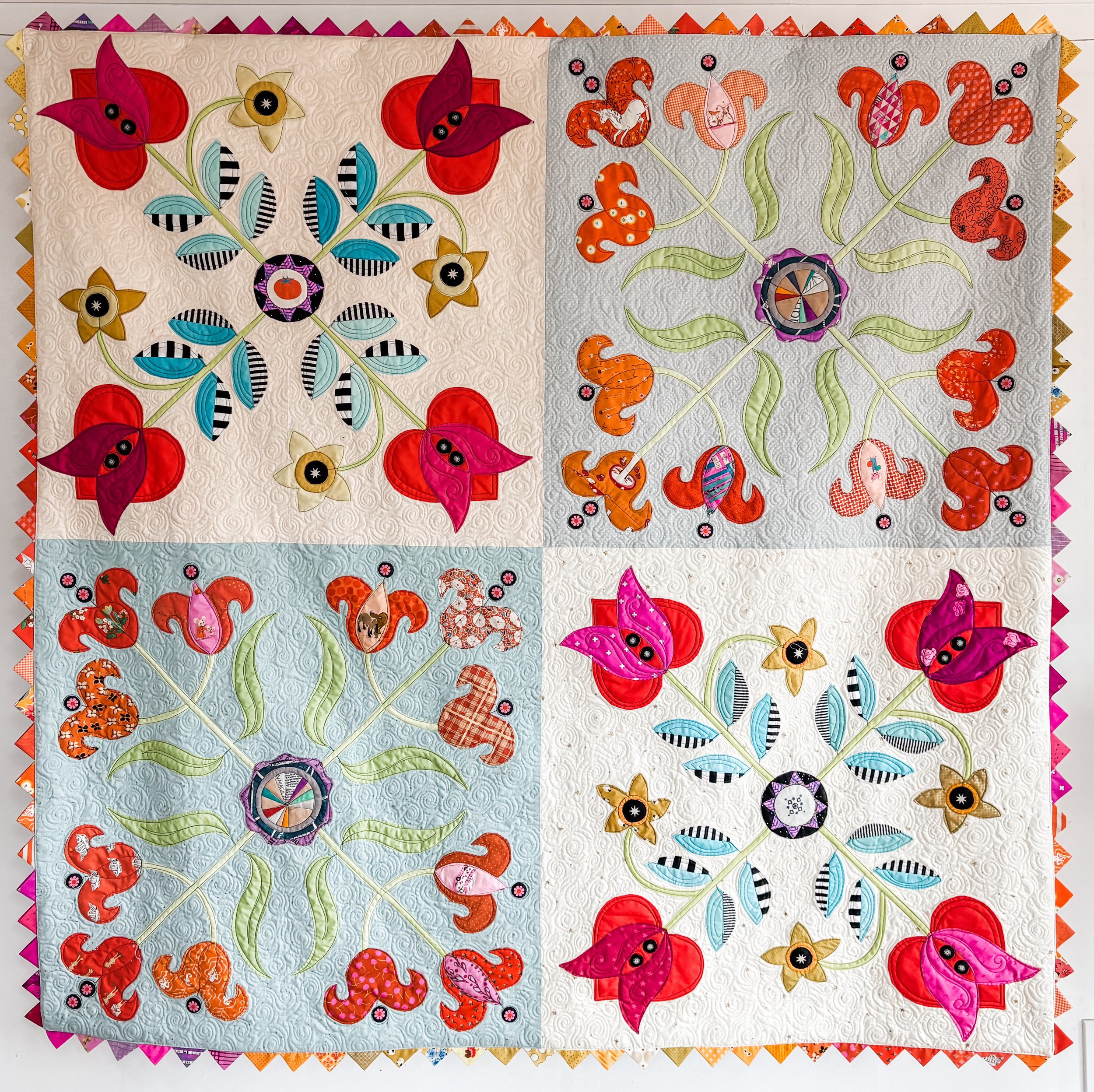Love Apples and Lovely Lilies made by Tia Curtis. I combined two of my large scale four block applique designs to make this quilt. I also wanted to add prairie points. I custom quilted this quilt on my longarm.