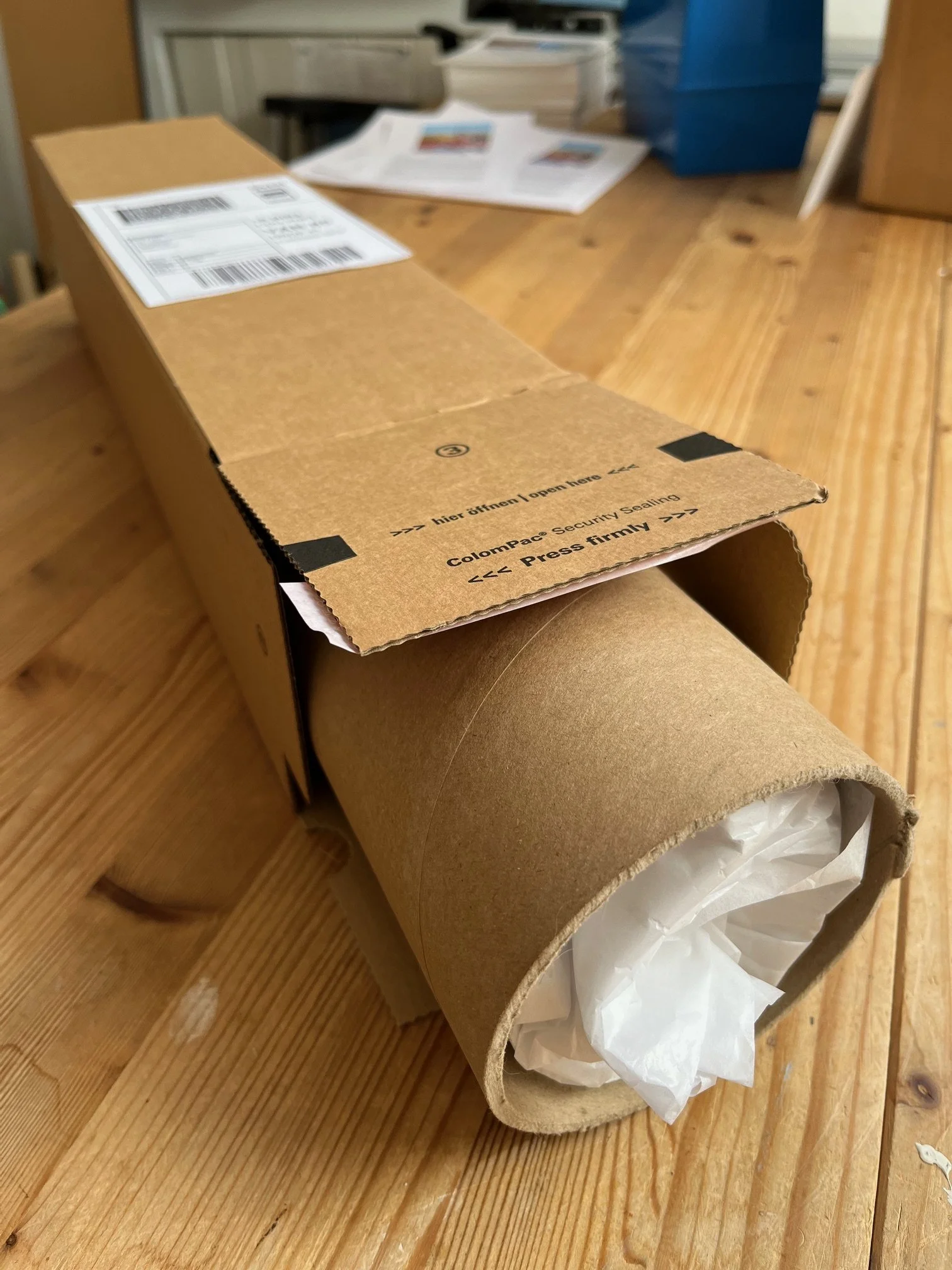 Photo showing print rolled in tissue paper, inserted in a cardboard tube, then placed inside a long square tube.