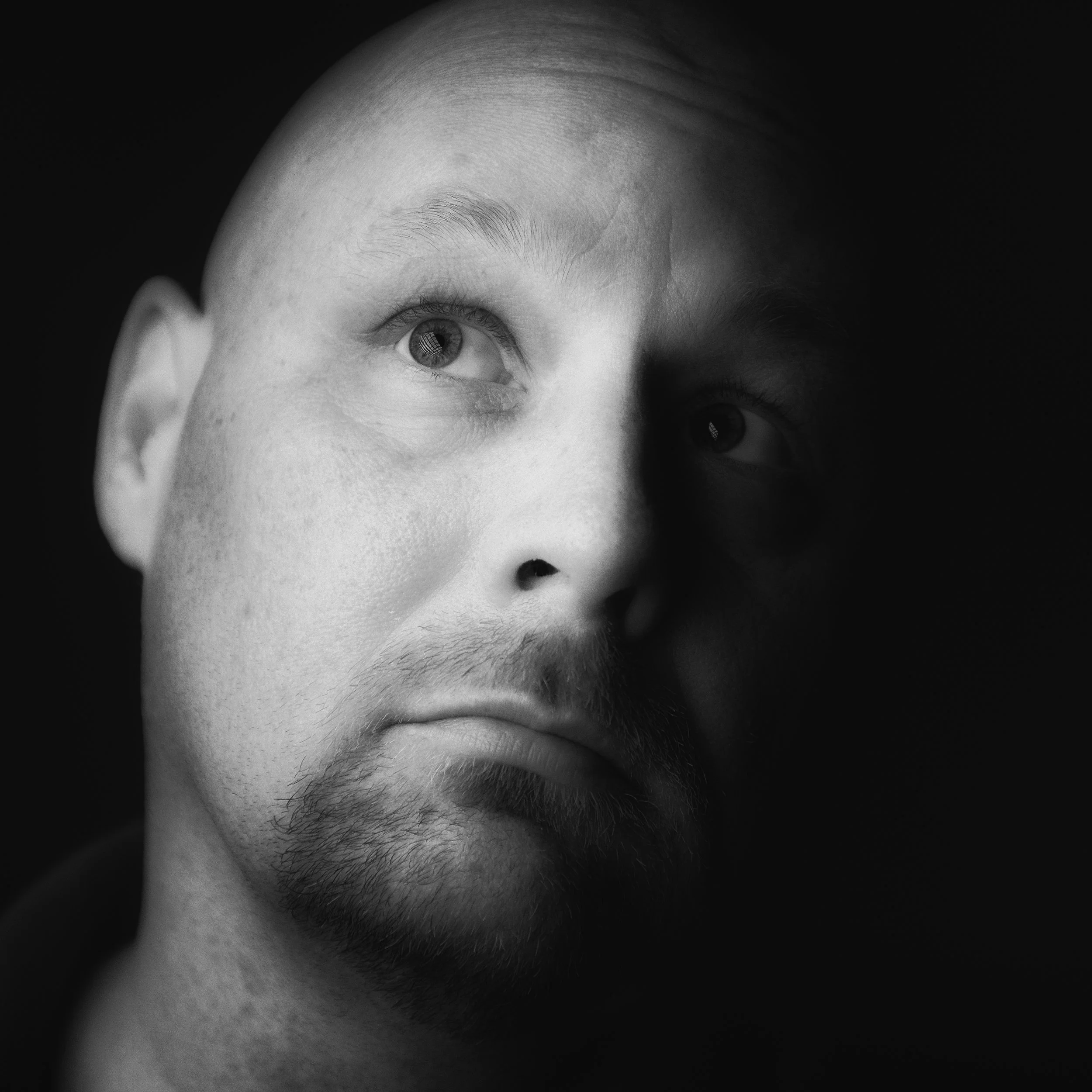 Black and white self portrait of photographer James Fike illuminated with directional lighting.