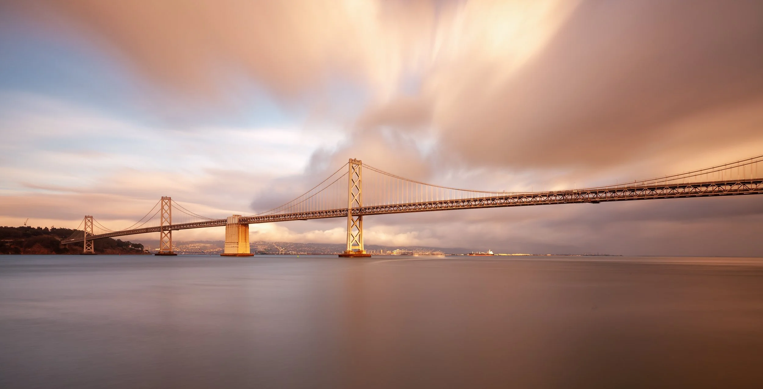 Quiet Over the Bay

 

 The San Francisco–Oakland Bay Bridge stretches across the bay in a long-exposure evening view. The bridge remains one of the central engineered landmarks of the Bay Area. 